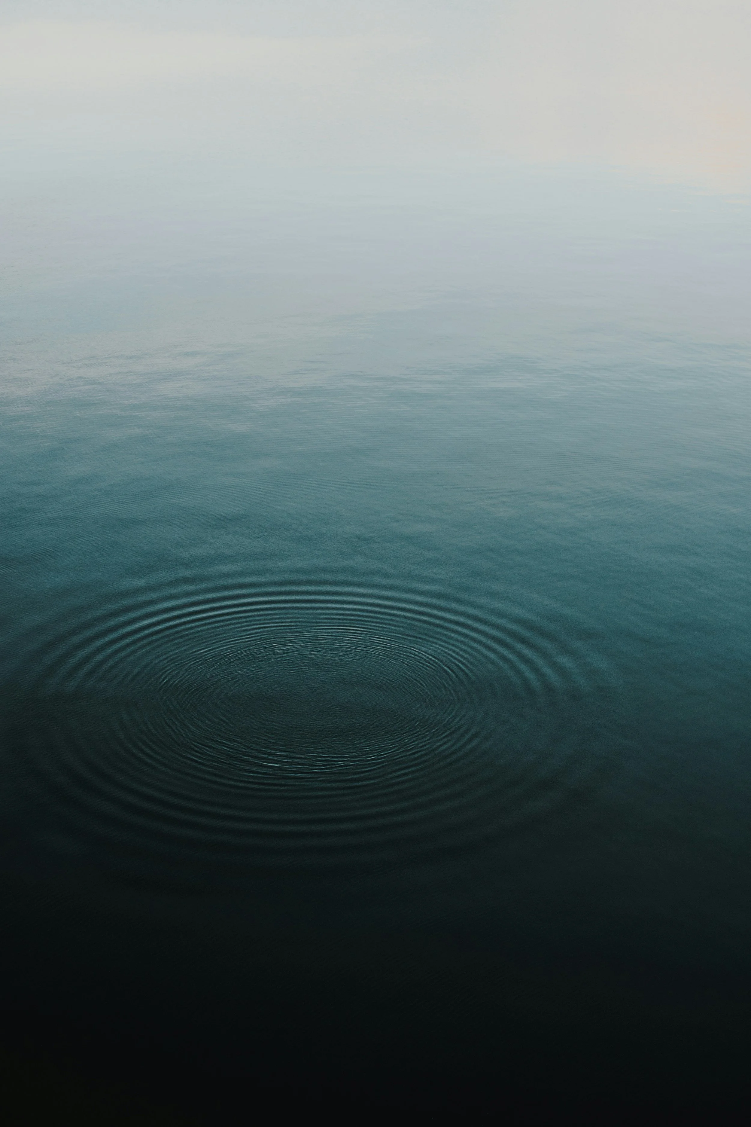Calm ocean water with ripples and a soft gradient sky at the horizon.