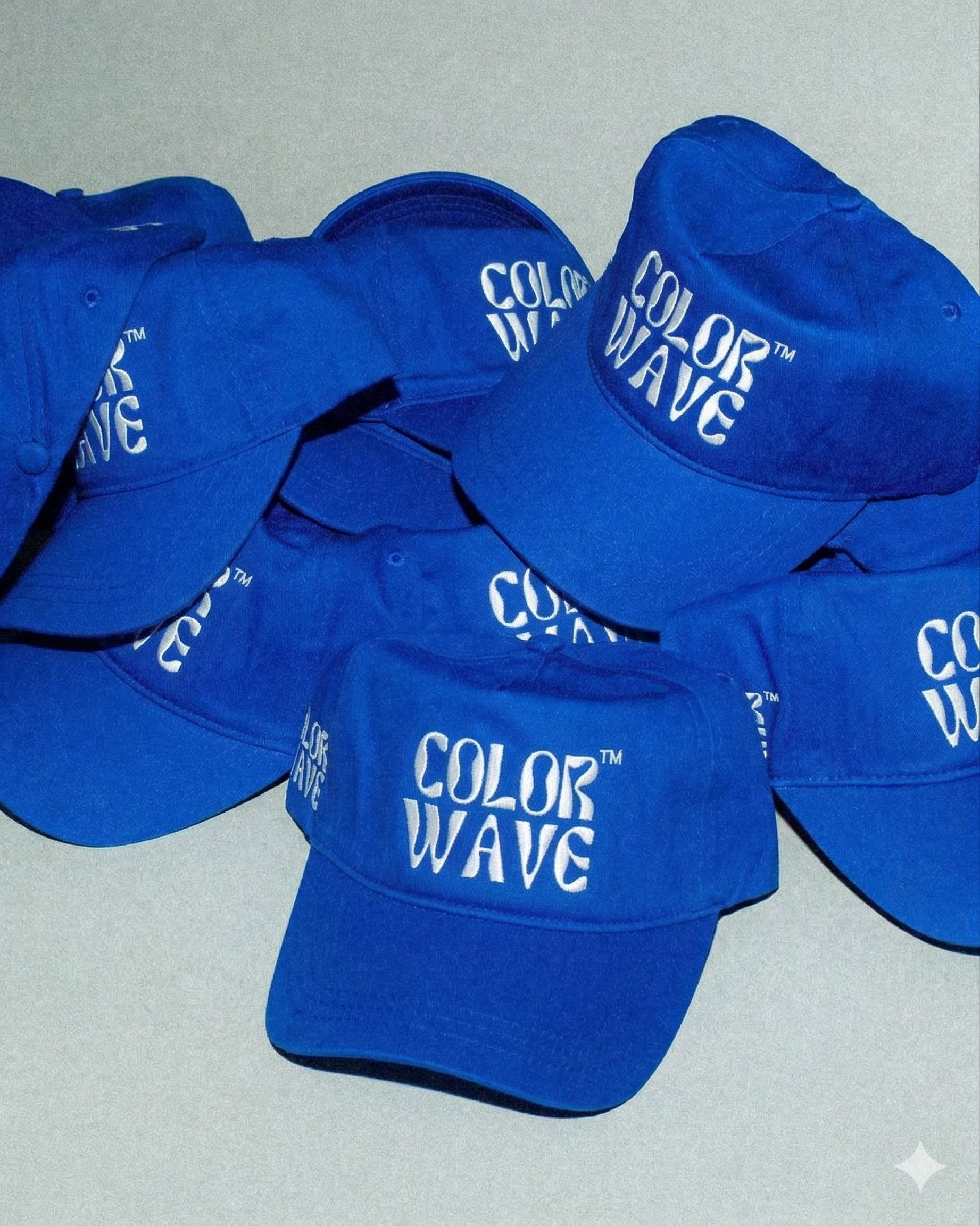 Multiple blue baseball caps with the words 'COLOR WAVE' printed in white on front.
