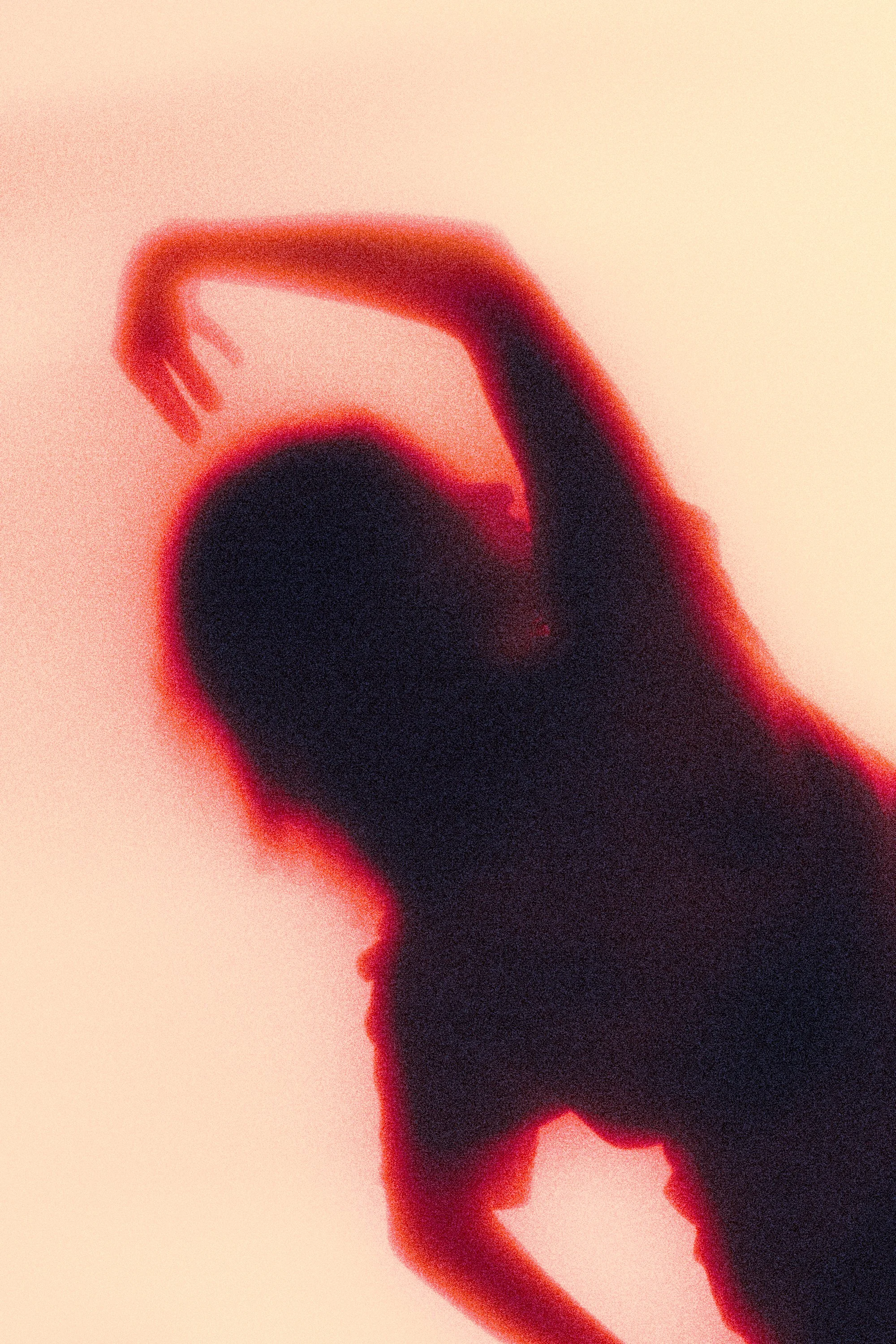 Abstract image with a person stretching or dancing, in red and black tones, with a blurred, artistic effect.