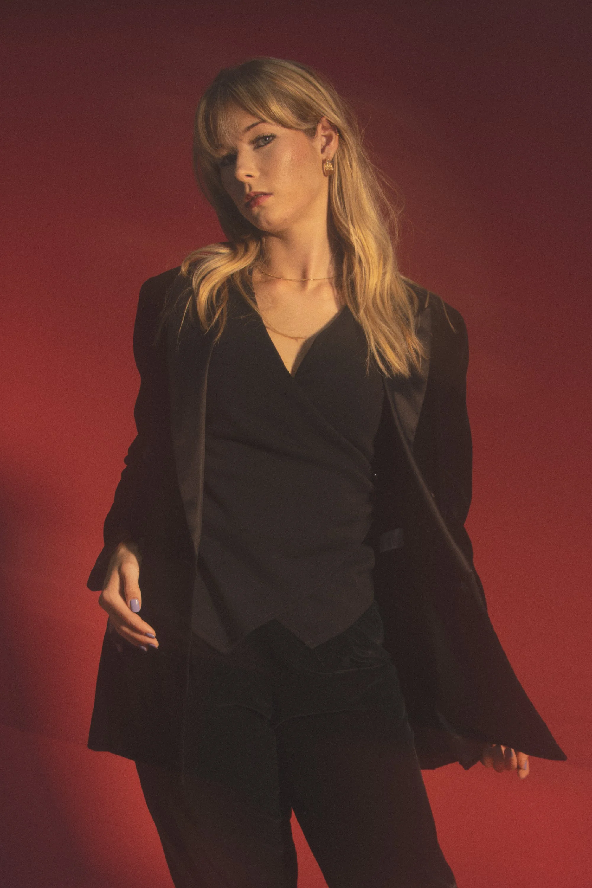 A woman in black clothing standing against a red background