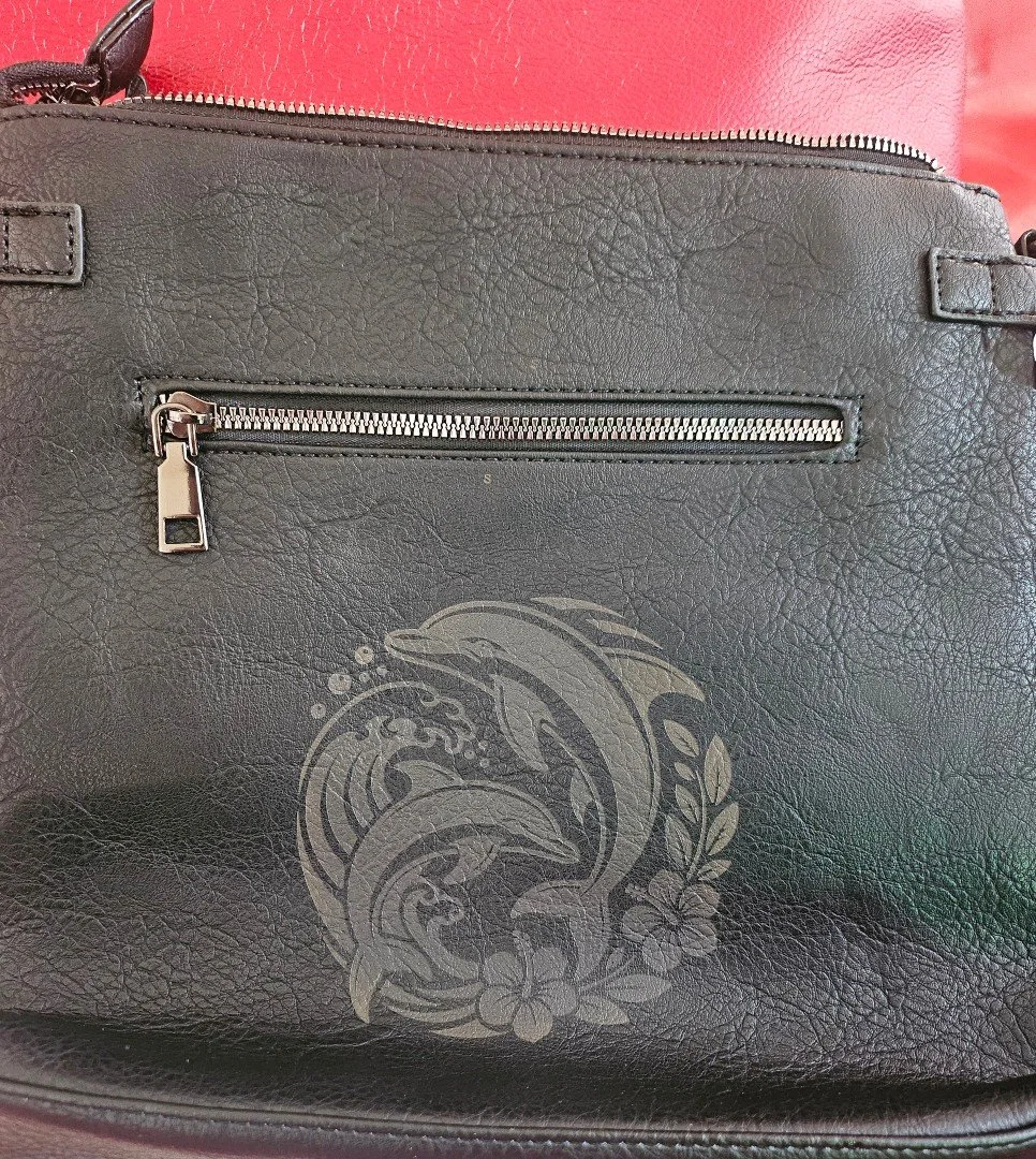 Detailed, elegant, and built to last. 🐬 Custom laser etching brings this intricate dolphin design directly onto sleek vegan leather. Adding a personalized touch to everyday accessories has never looked better!

Looking to personalize your bag, journ