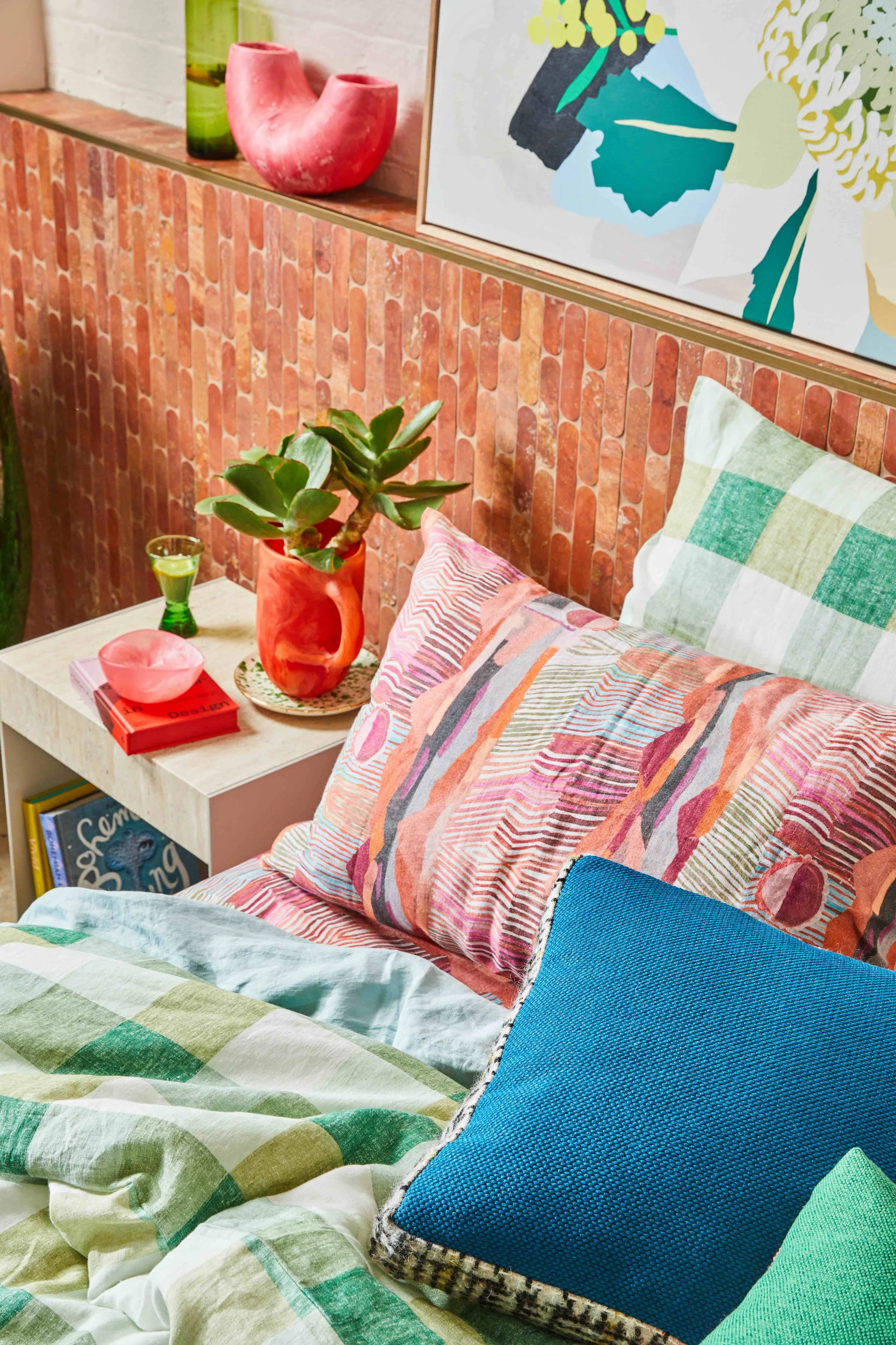Bedroom styled by Blake & Co Studio with layered linen bedding, gingham and a patterned pillowcase against a terracotta brick wall