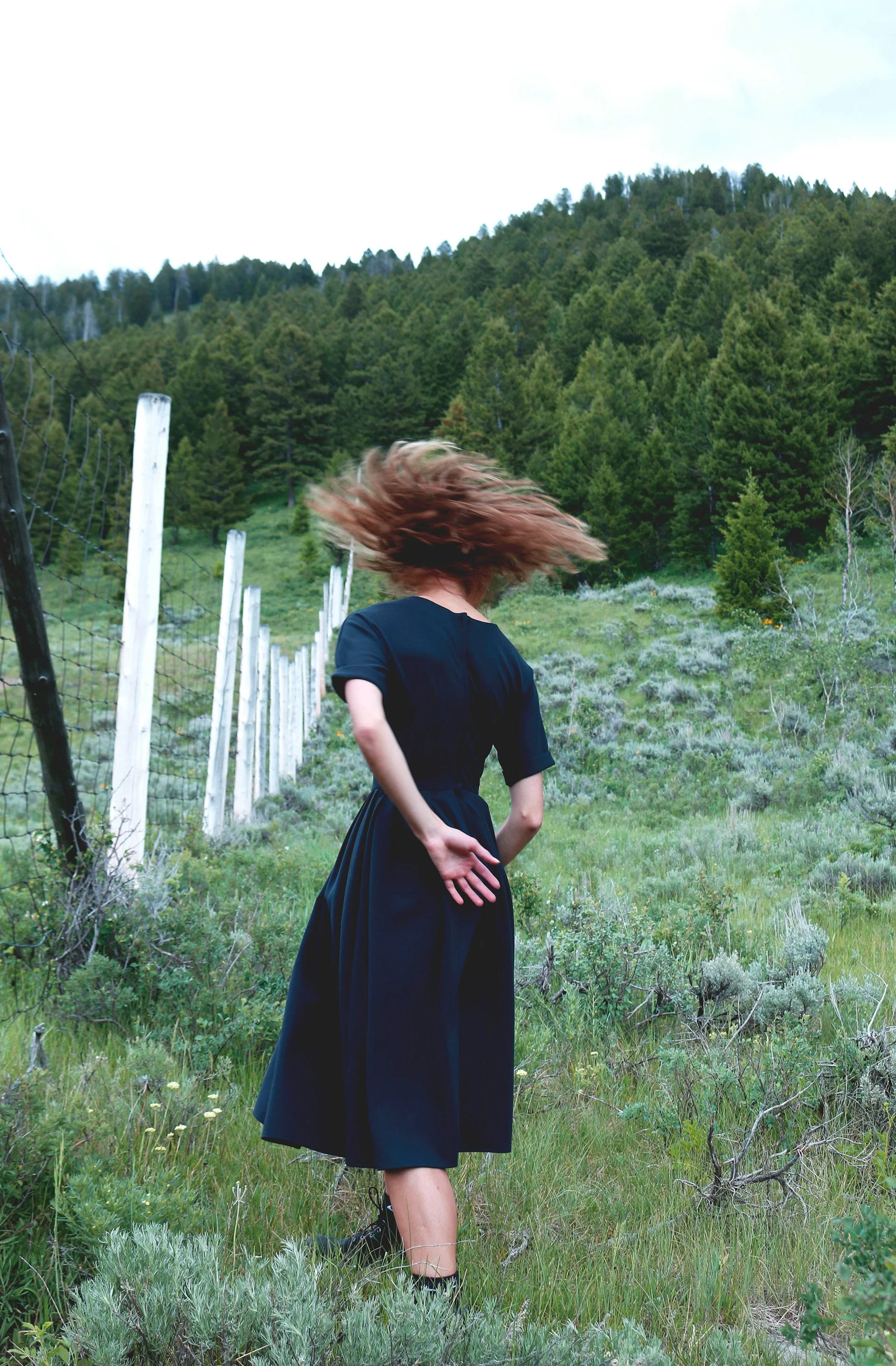 Michaela Ellingson dancing in a field with a navy dress on.