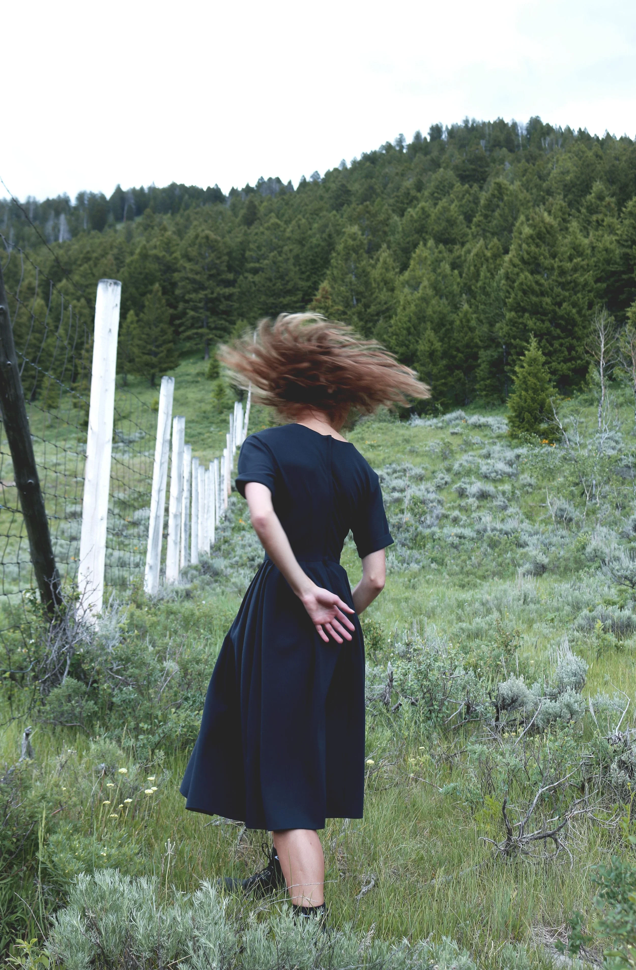 Michaela Ellingson dancing in a field with a navy dress on.