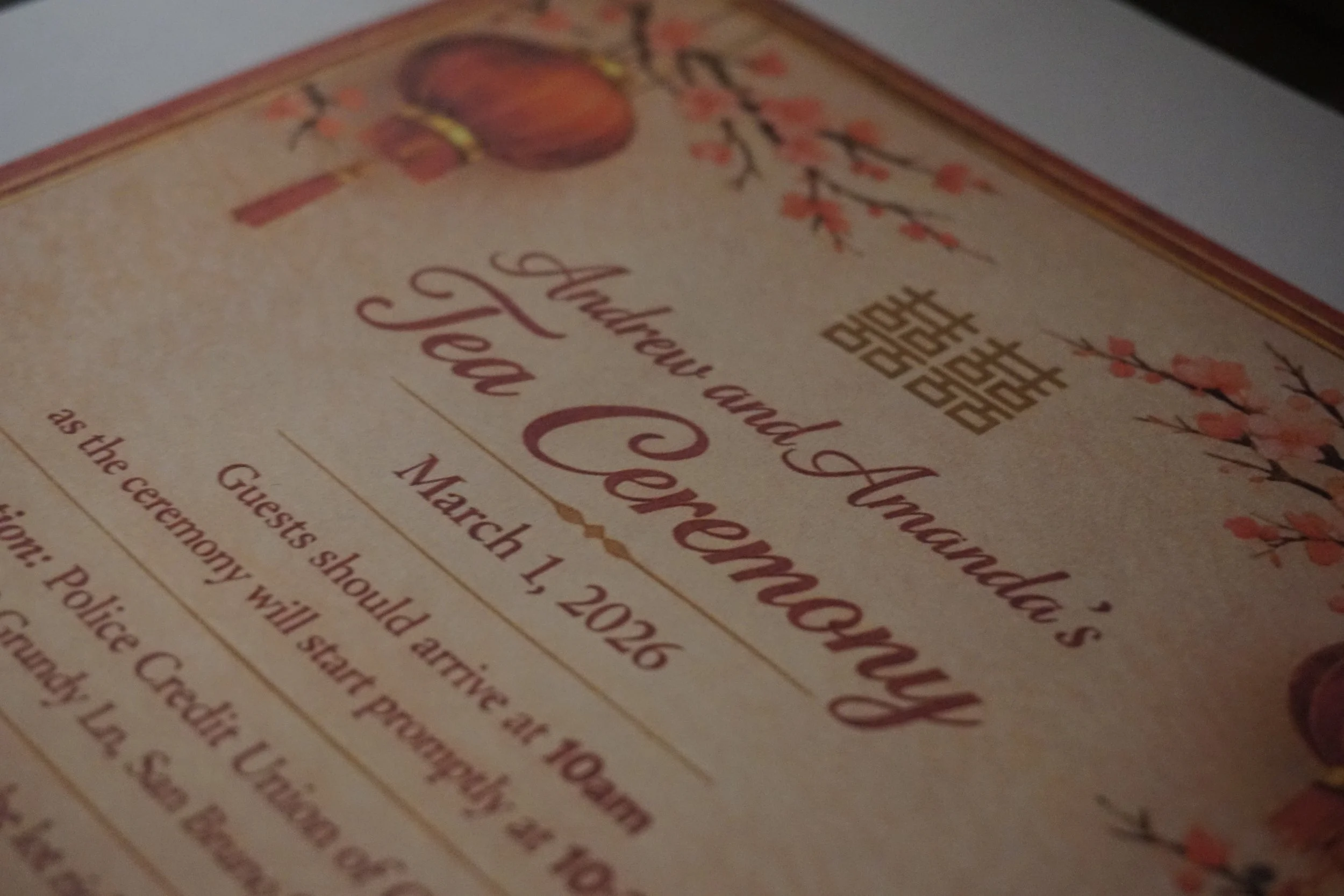 A wedding invitation featuring elegant calligraphy, cherry blossom illustrations, and an Asian-inspired gold pattern.
