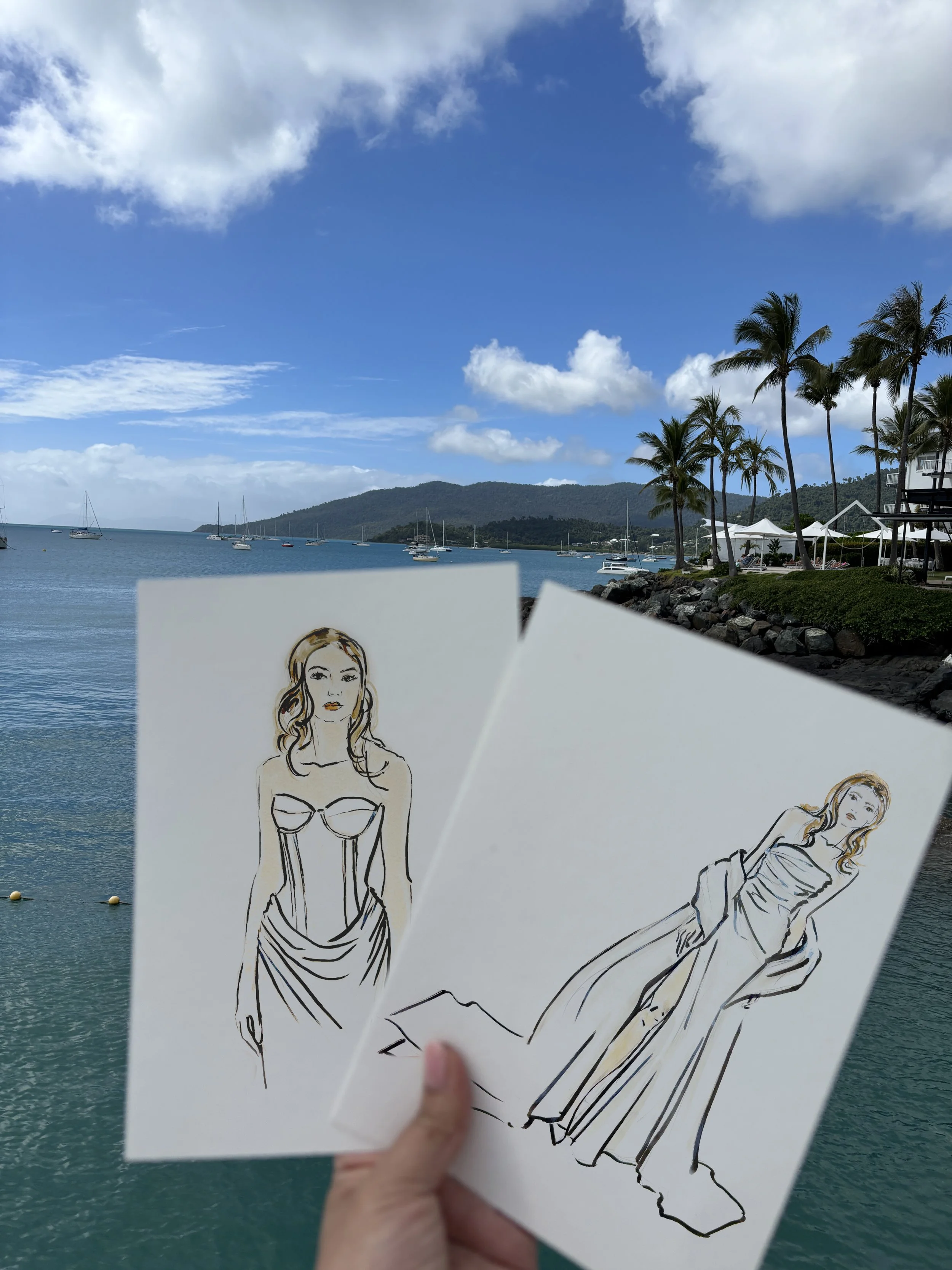 Two hand-drawn bridal fashion illustrations featuring wedding dresses against a coastal backdrop.