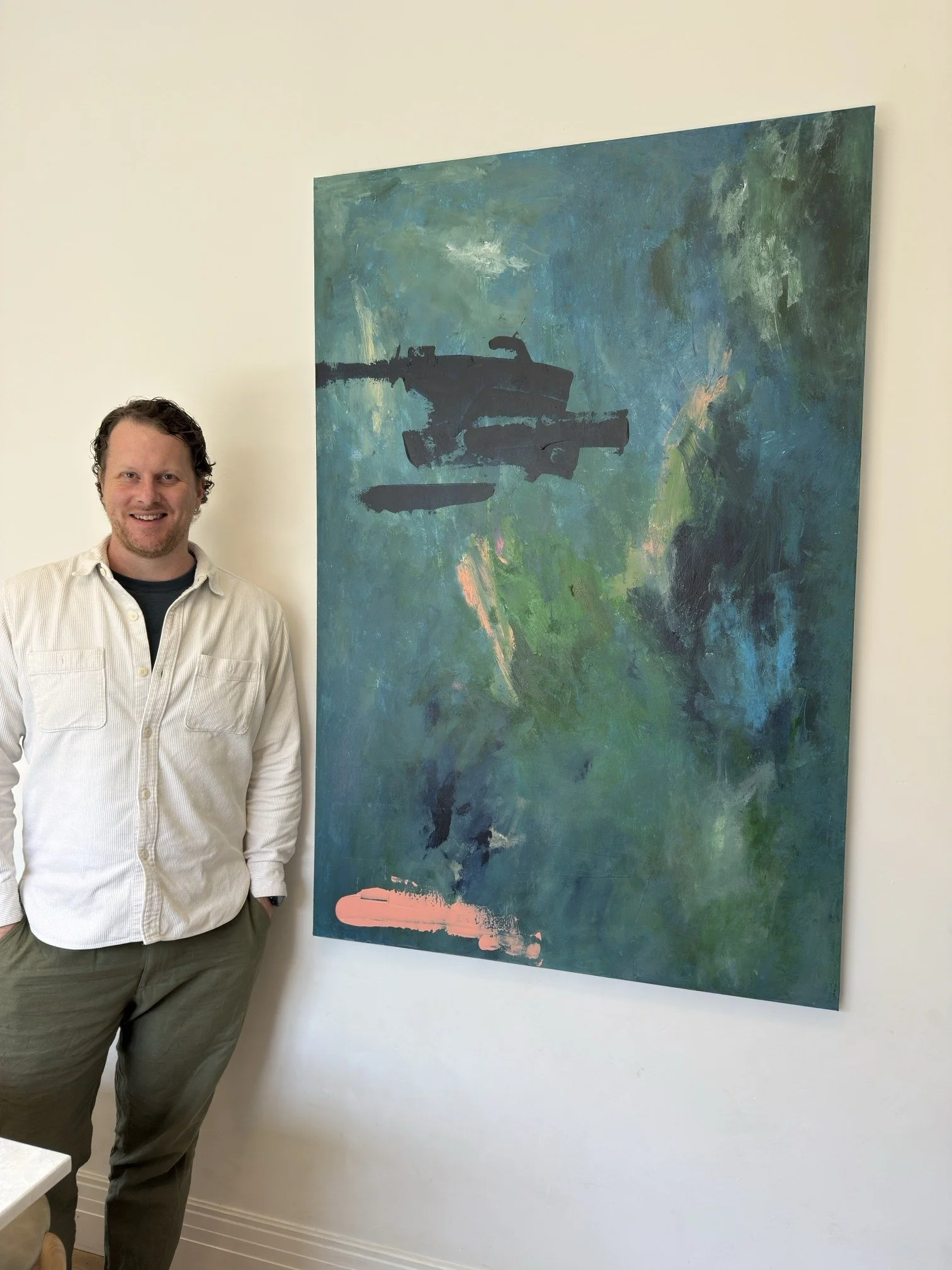 Thomas Cain standing beside his commissioned painting B, a large blue-green abstract, 100 x 150 cm