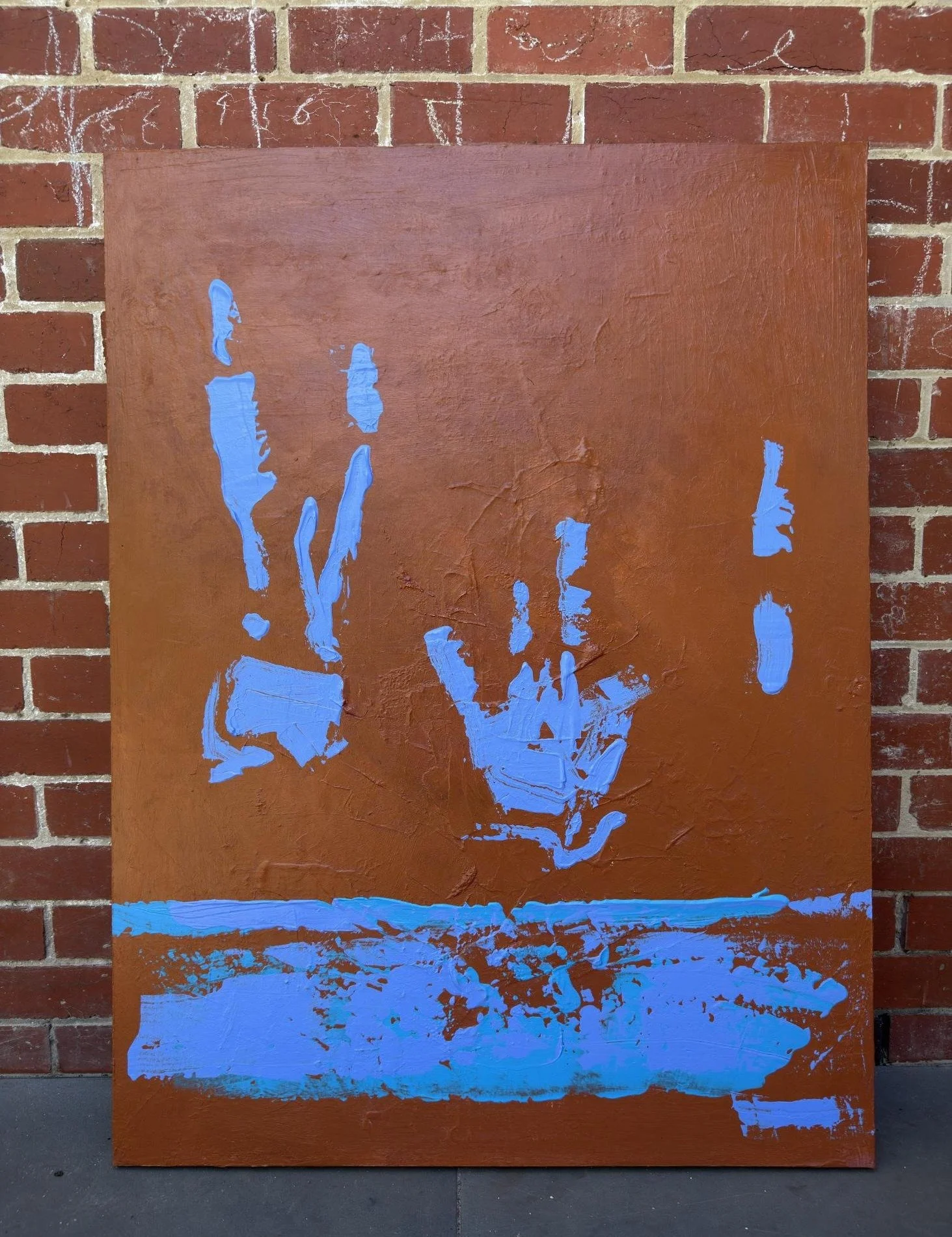 Blue Lilies by Thomas Cain leaning against a red brick wall