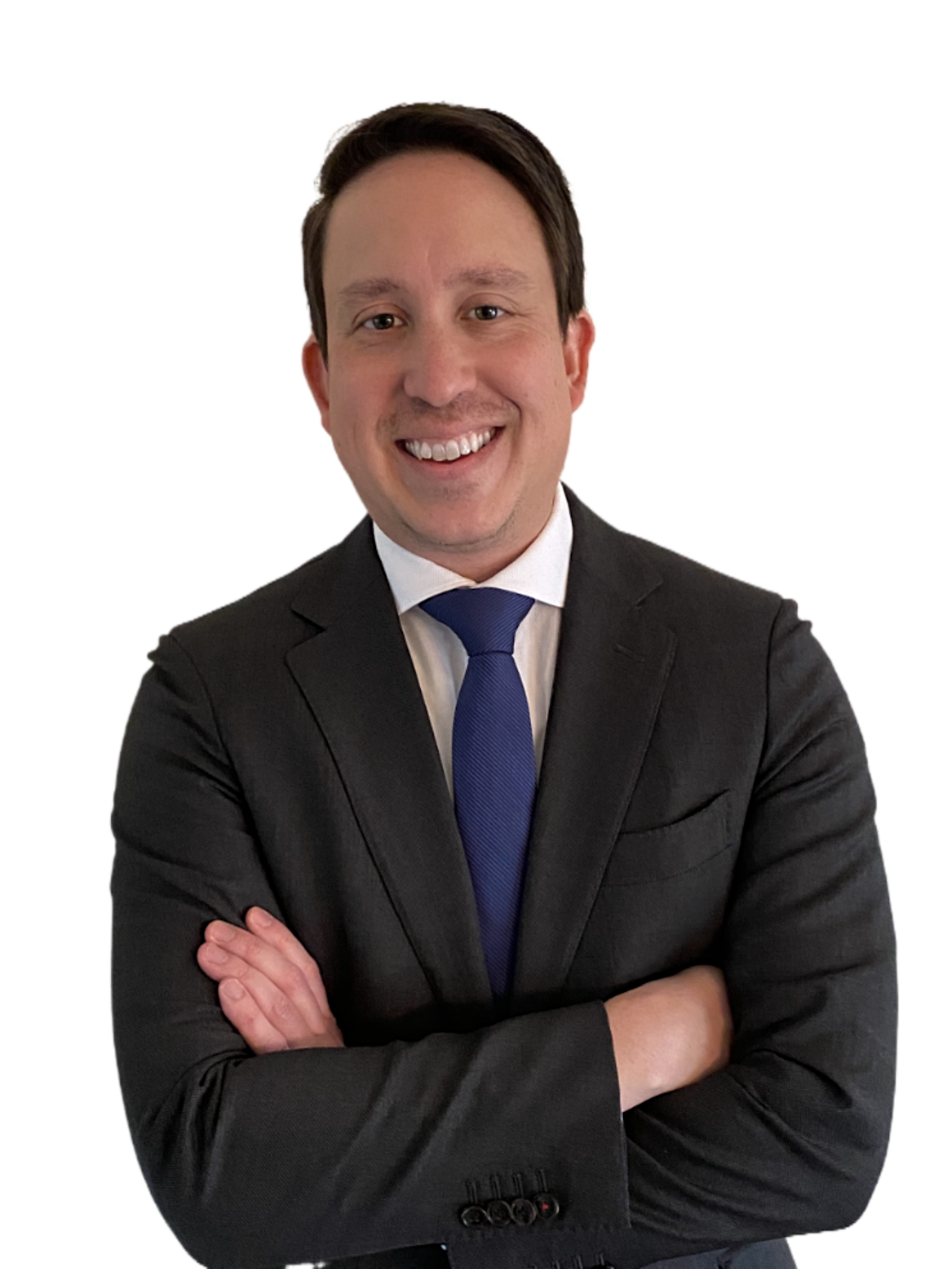 A smiling man in a black suit, white shirt, and blue tie, standing with arms crossed.