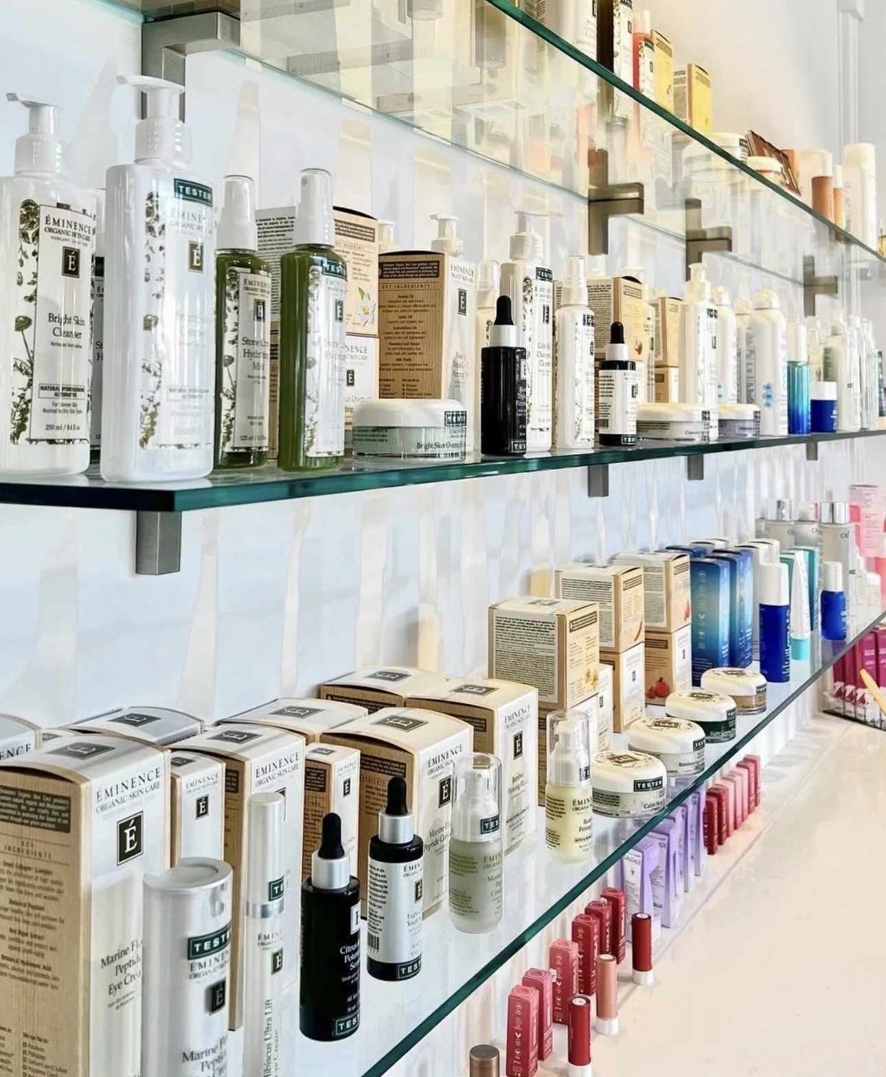 Display of skincare and beauty products on glass shelves in a store.