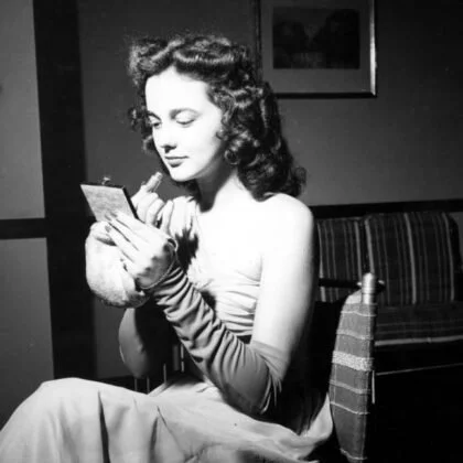 A woman sitting on a bench, looking at her phone.