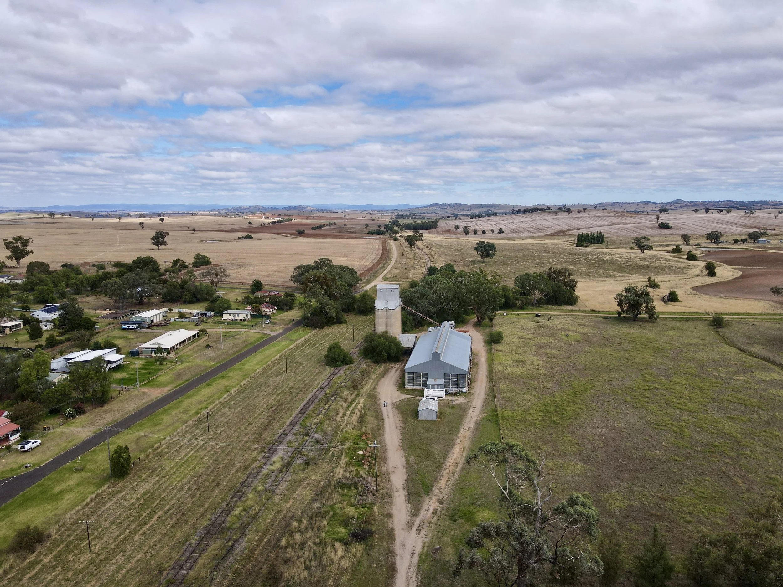 Aerial view of a rural landscape with a farm and surrounding fields, under a cloudy sky.