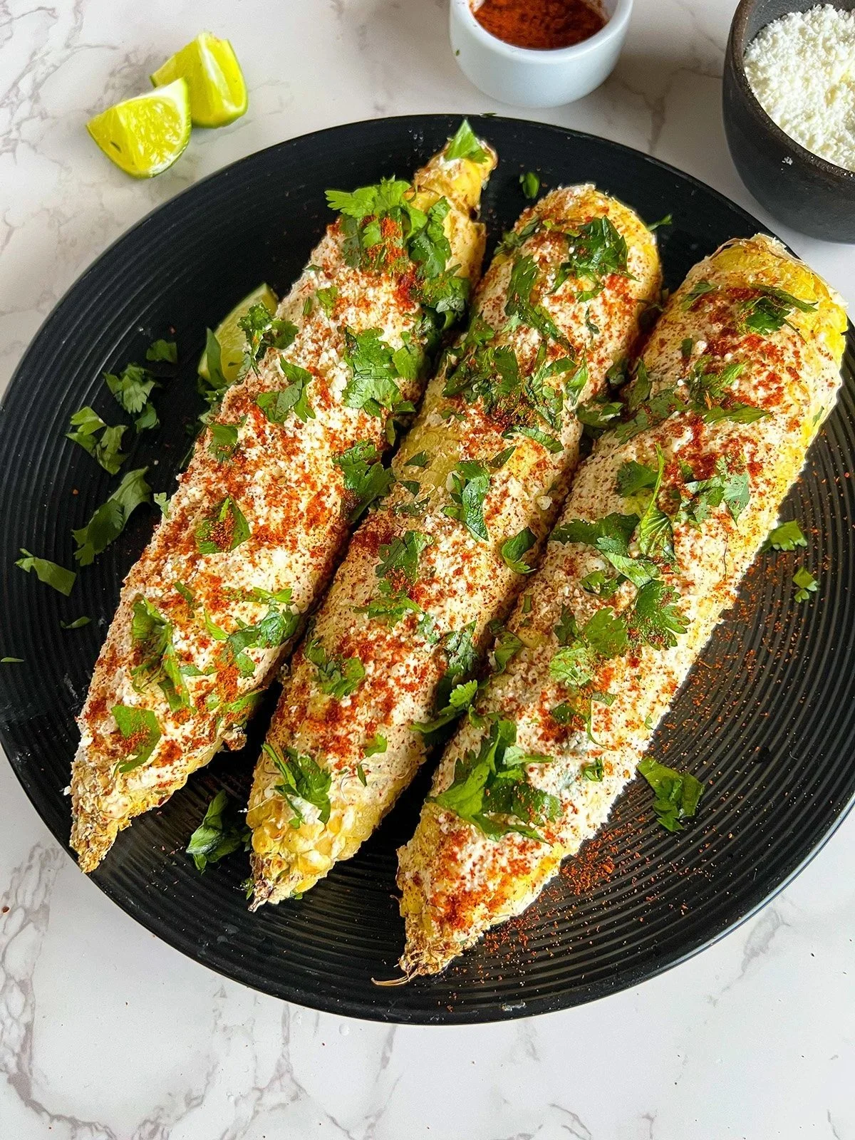 Tandoori Mexican Street Corn topped with creamy sauce, Indian spices, and fresh herbs