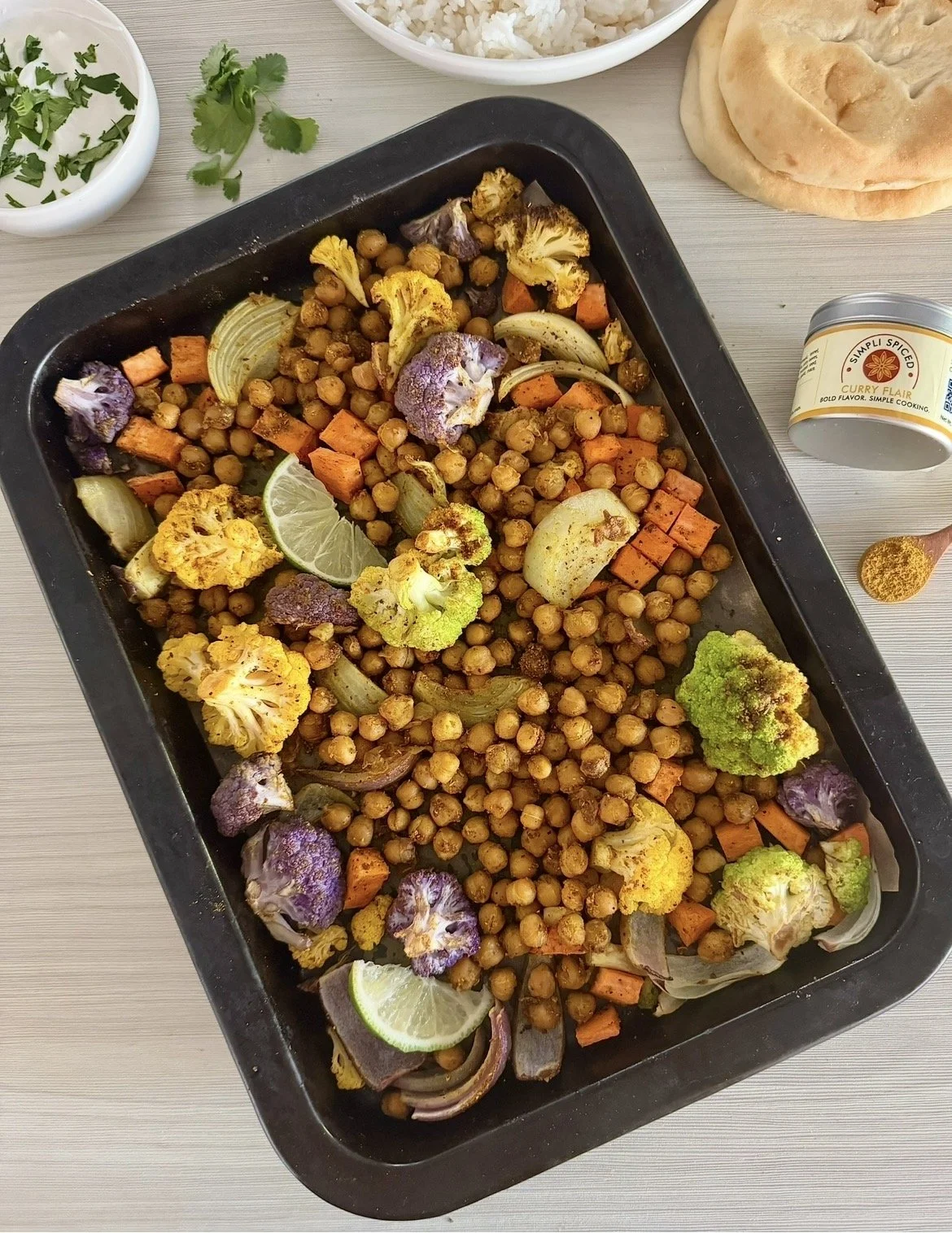 Sheet pan curry vegetables and chickpeas roasted with spices, served with rice and naan