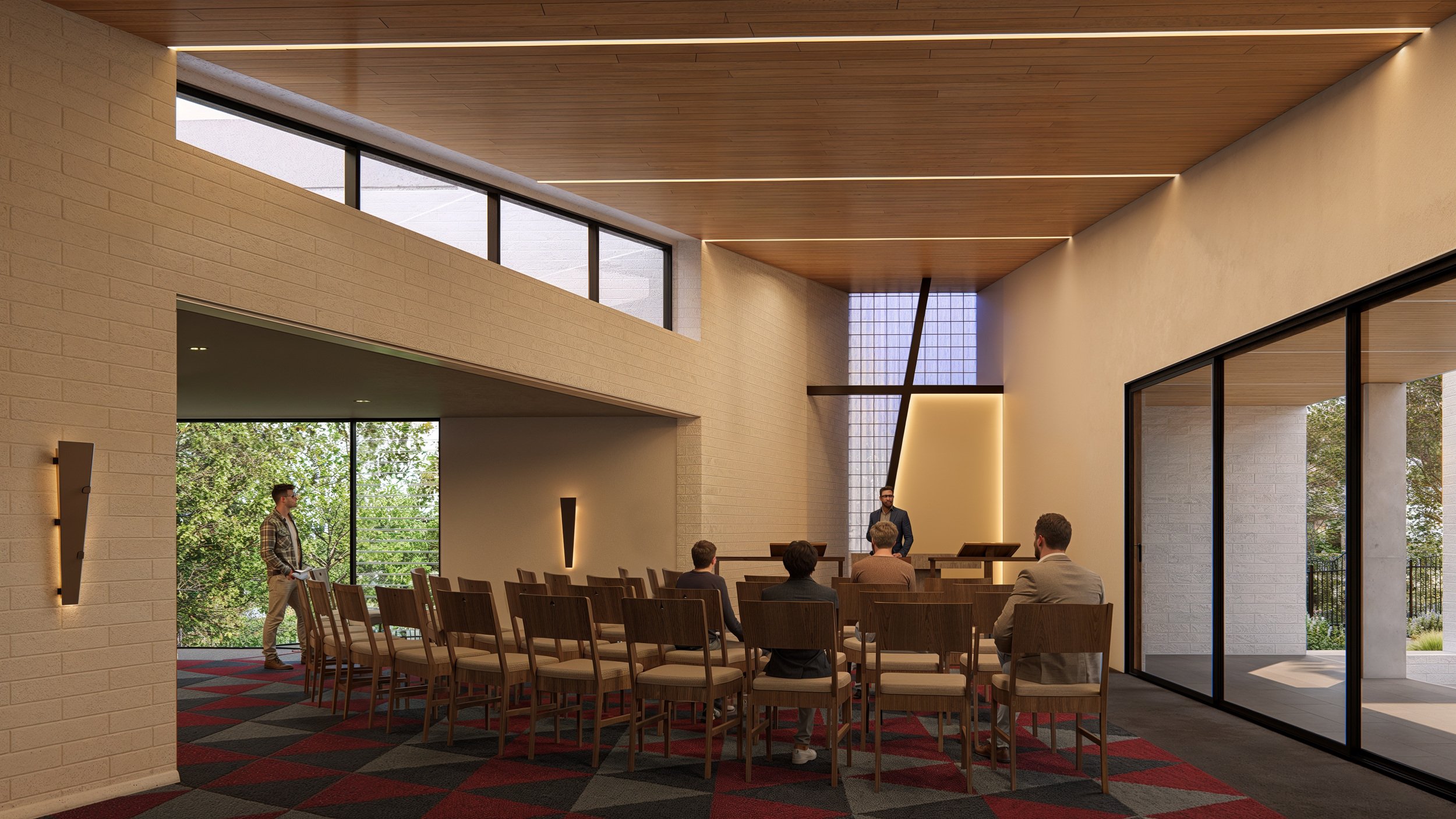 Interior of a modern meeting room with wood-paneled ceiling, large windows, and a speaker at a podium addressing a small audience seated in wooden chairs.
