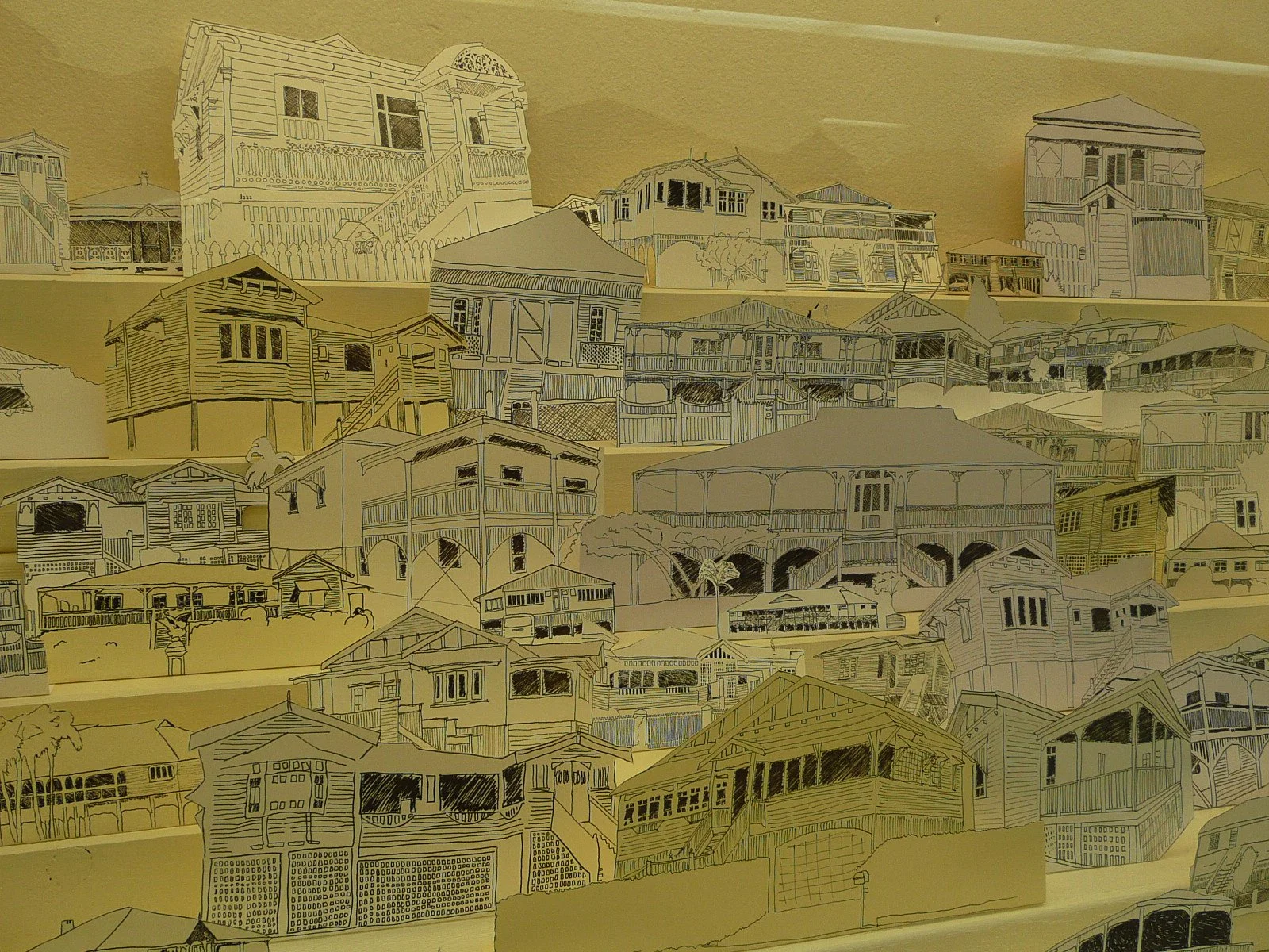 A collage of multiple sketches of houses, including front views and side views, arranged on a wall.