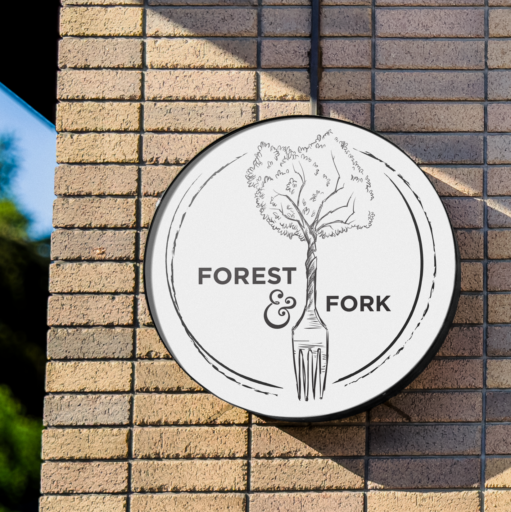 Sign on brick wall featuring a tree with a fork as the trunk, with the words 'Forest & Fork'.