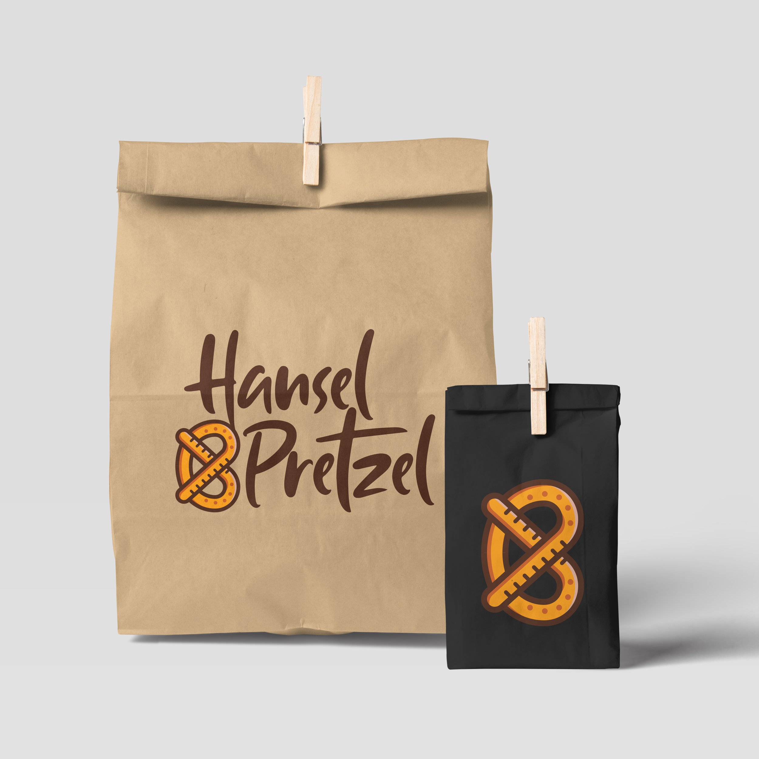 Two paper bags with 'Hansel Pretzel' logo and pretzel highlighting on a light gray background.