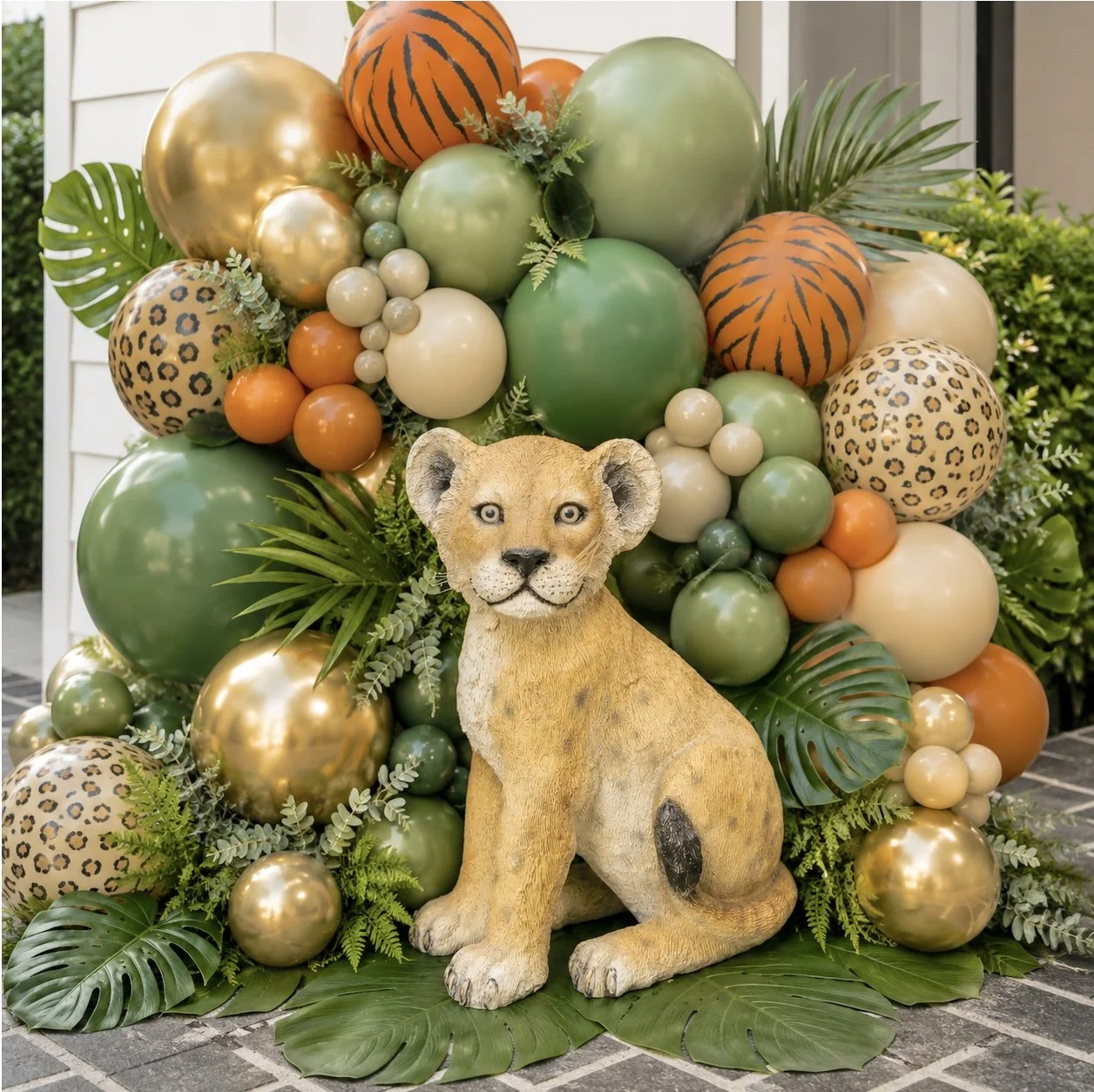 Decorative arrangement of two pink plastic flamingos, a lion cub figurine, and yellow flowers with green leaves against a beige textured backdrop.
