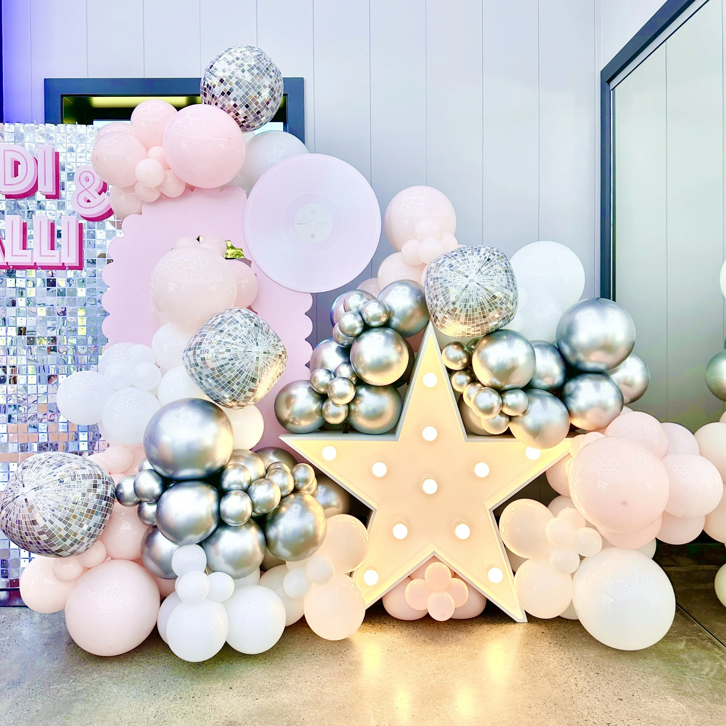 Decorative balloon wall around a large illuminated star for a disco themed kids party 