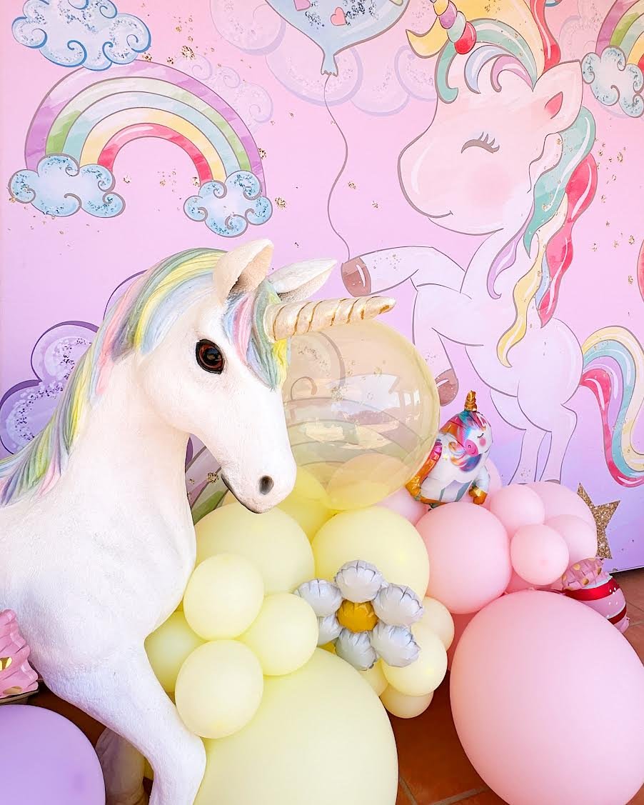 Life-size unicorn prop, a unicorn birthday backdrop and pastel balloon garland