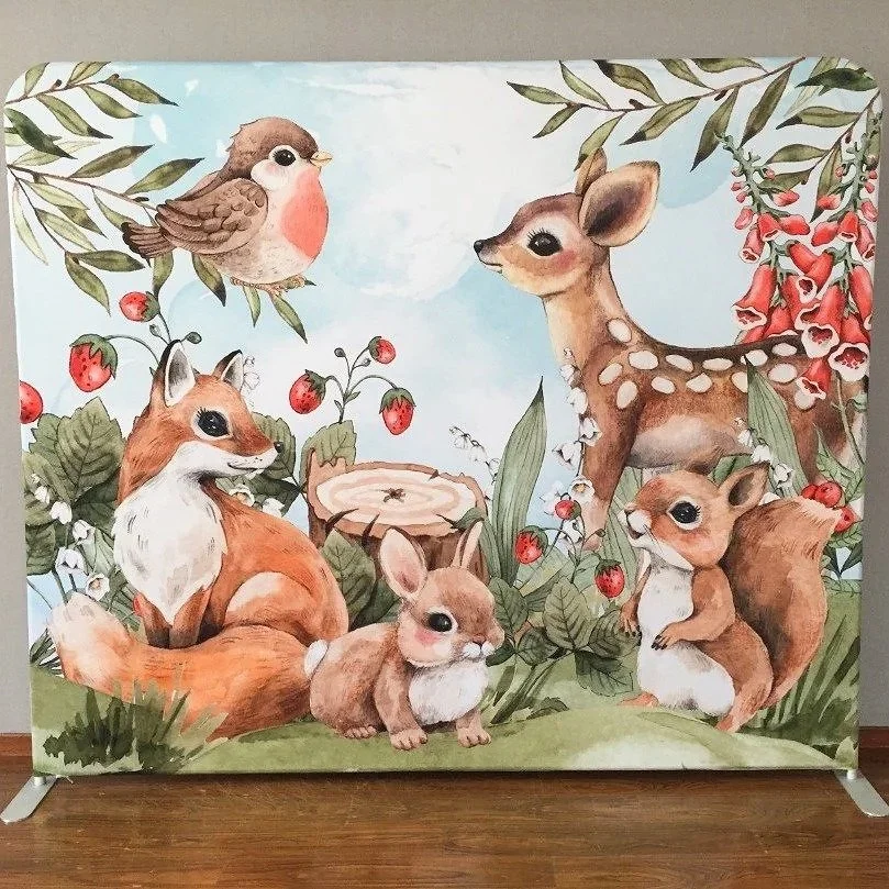 Woodland animals themed party backdrop including a bird, a fox, a rabbit, a deer, and a squirrel among bushes with red berries, alongside a tree stump and flowering plants