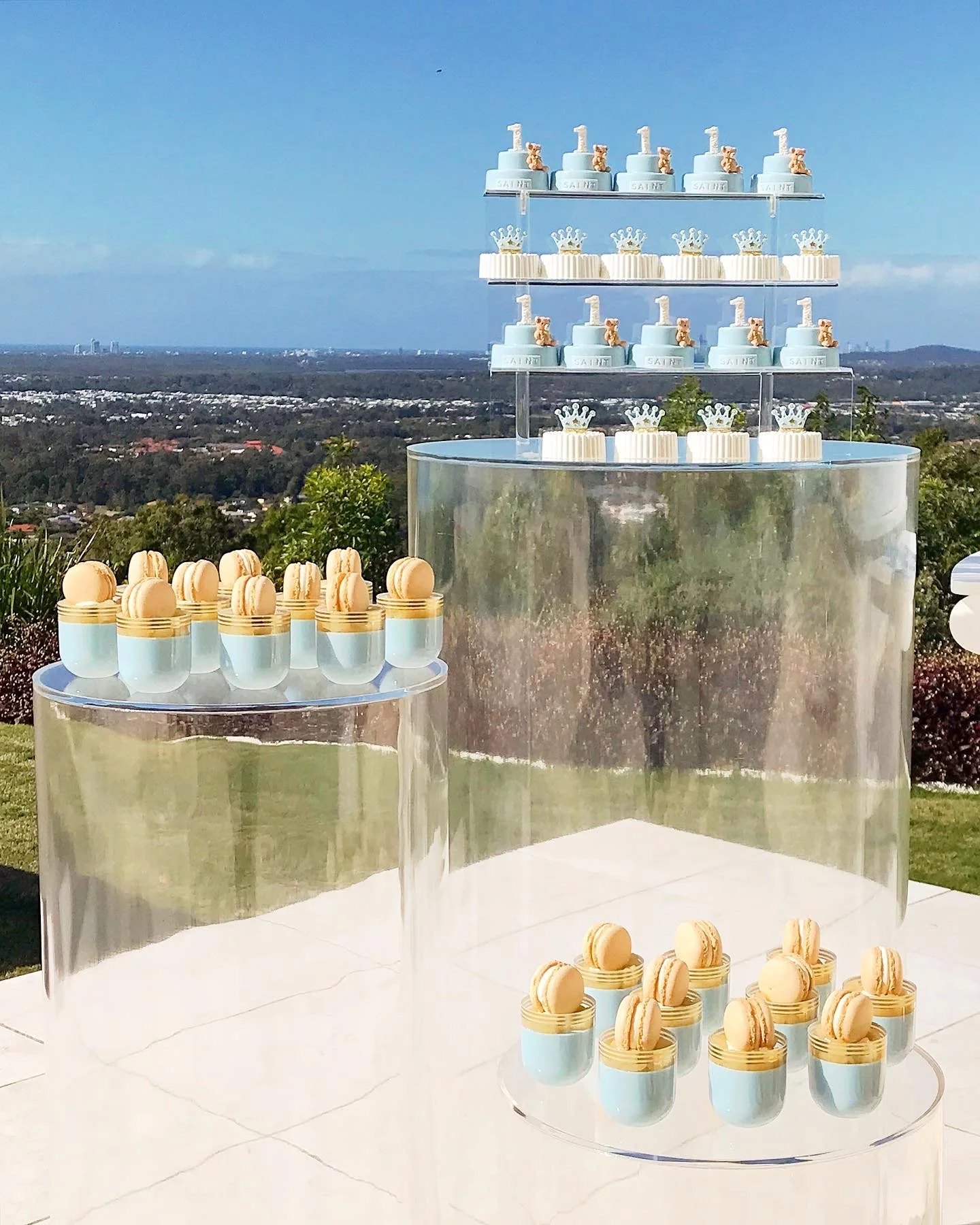 Clear cake plinths displaying elegant macarons and cake with crown toppers