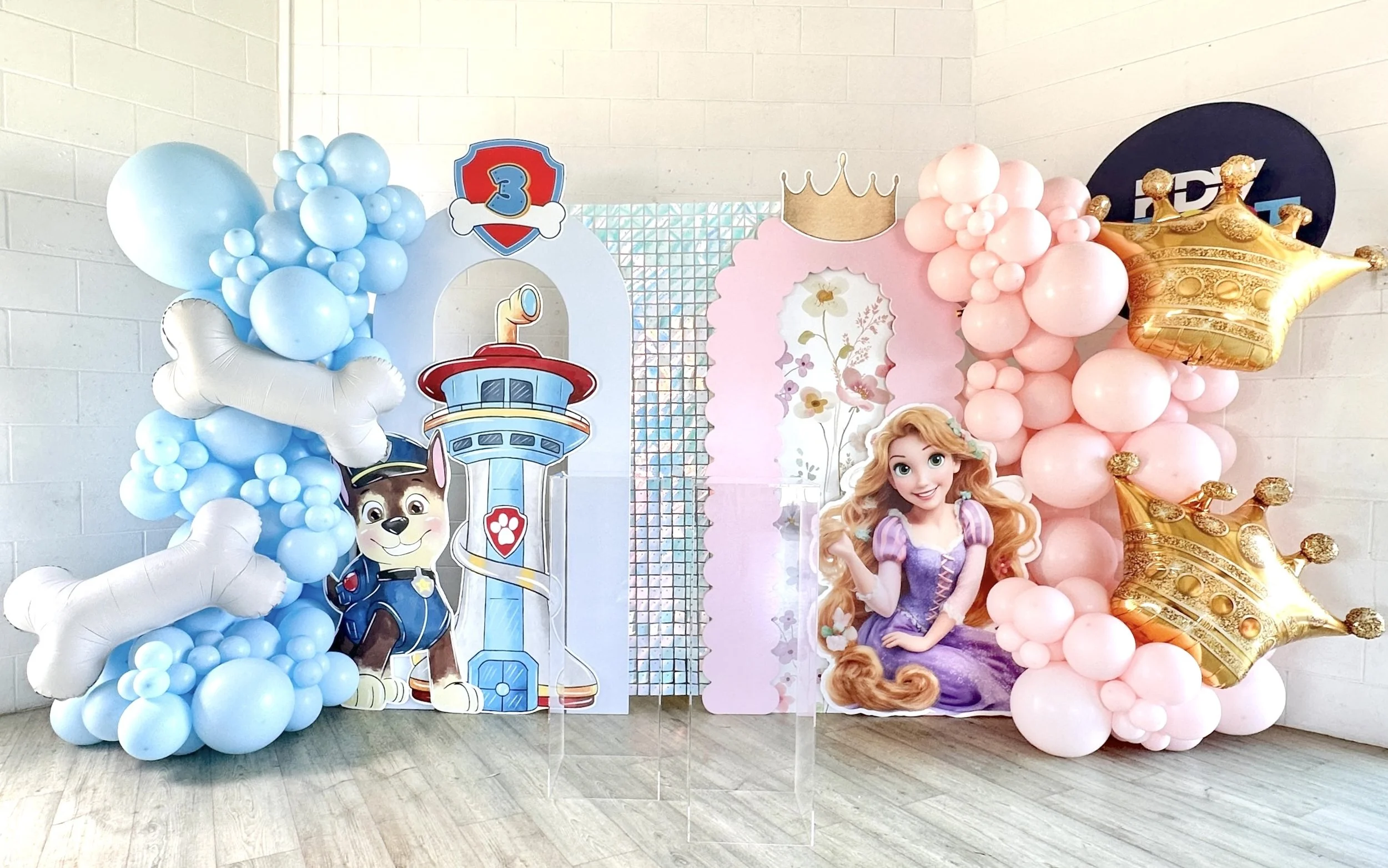 Decorations for a child's birthday party featuring a Disney Princess Rapunzel theme, with balloons, character cutouts, and a pink and blue color scheme.