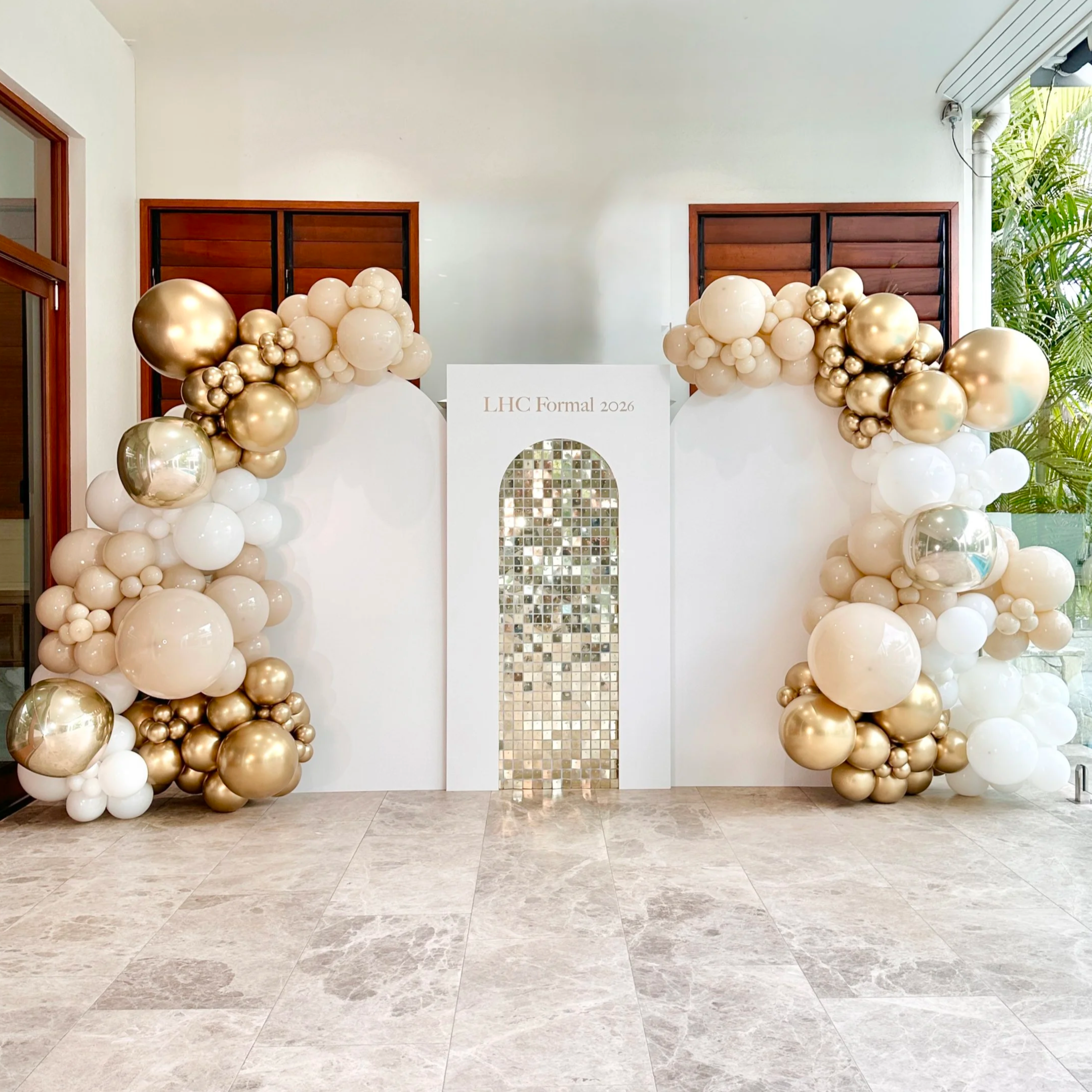 Decorative balloon arch with white and gold balloons at a formal event with a sign that reads "LHC Formal 2026".