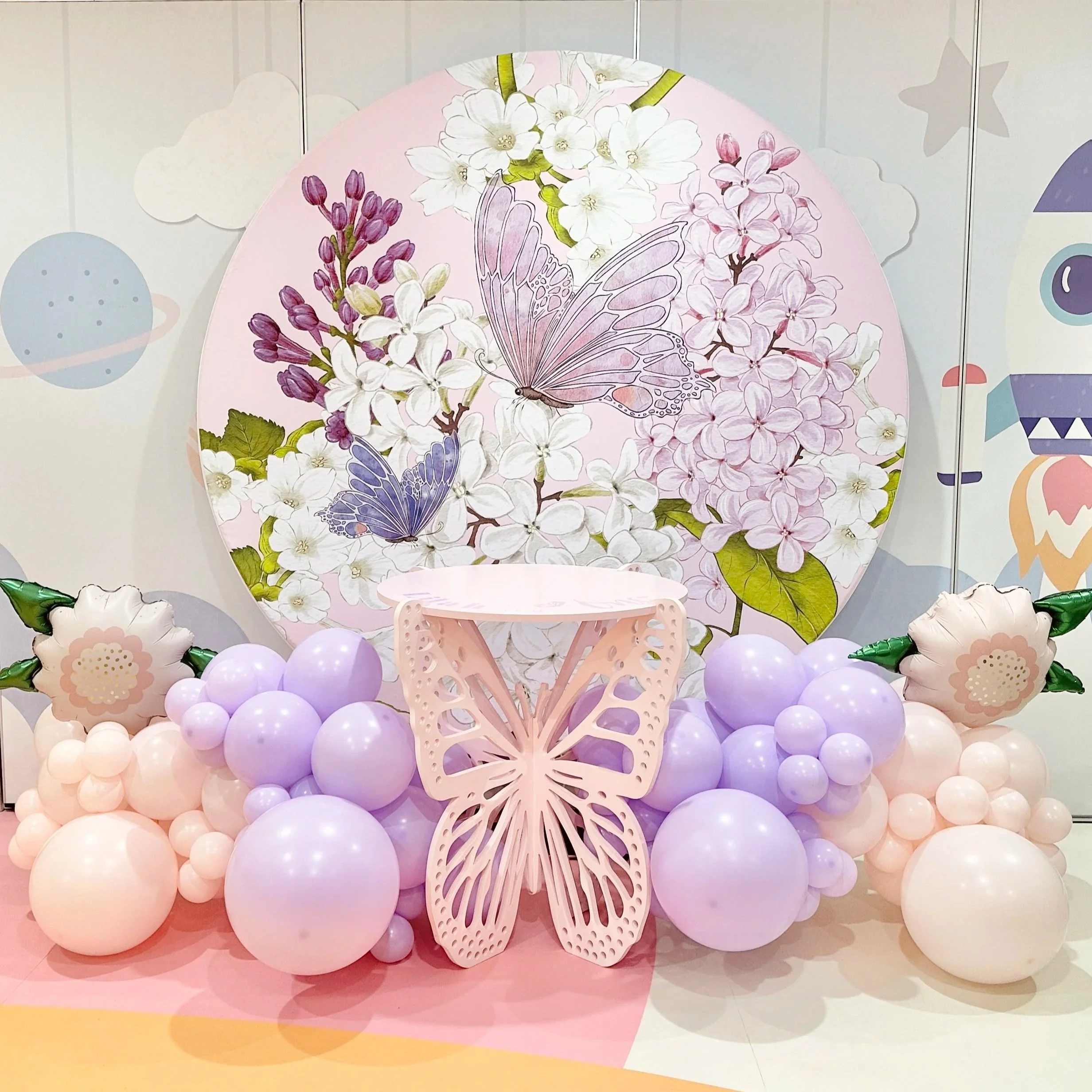 First birthday setup with round backdrop, balloon garland and butterfly cake table