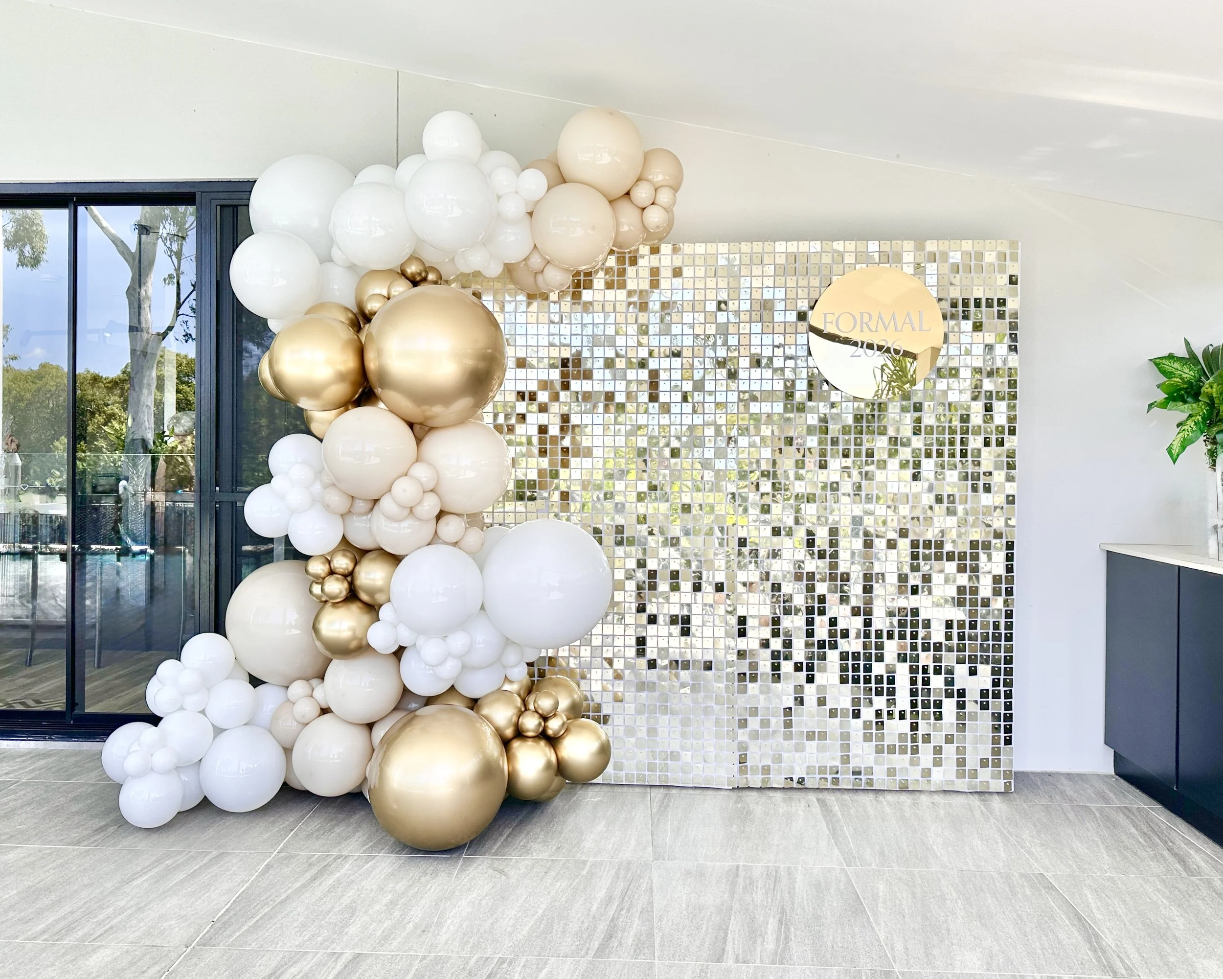 Gold shimmer wall and a balloon arrangement of white, gold, and beige for a pre formal party