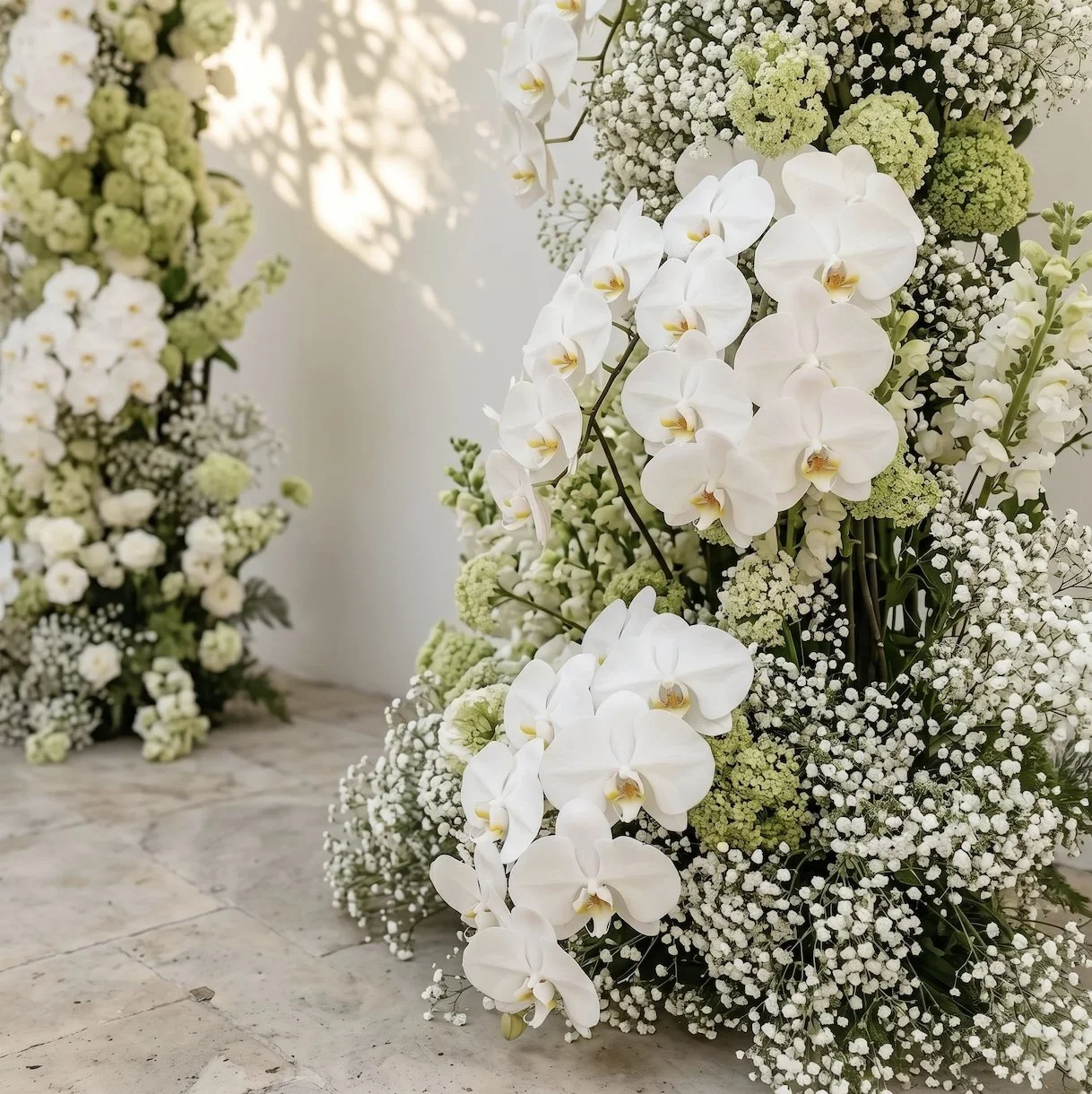 White orchid floral arrangement with baby's breath and green accents.
