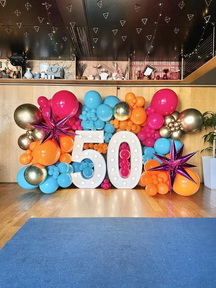 Colourful balloon wall celebrating a 50th birthday with large light up number 50