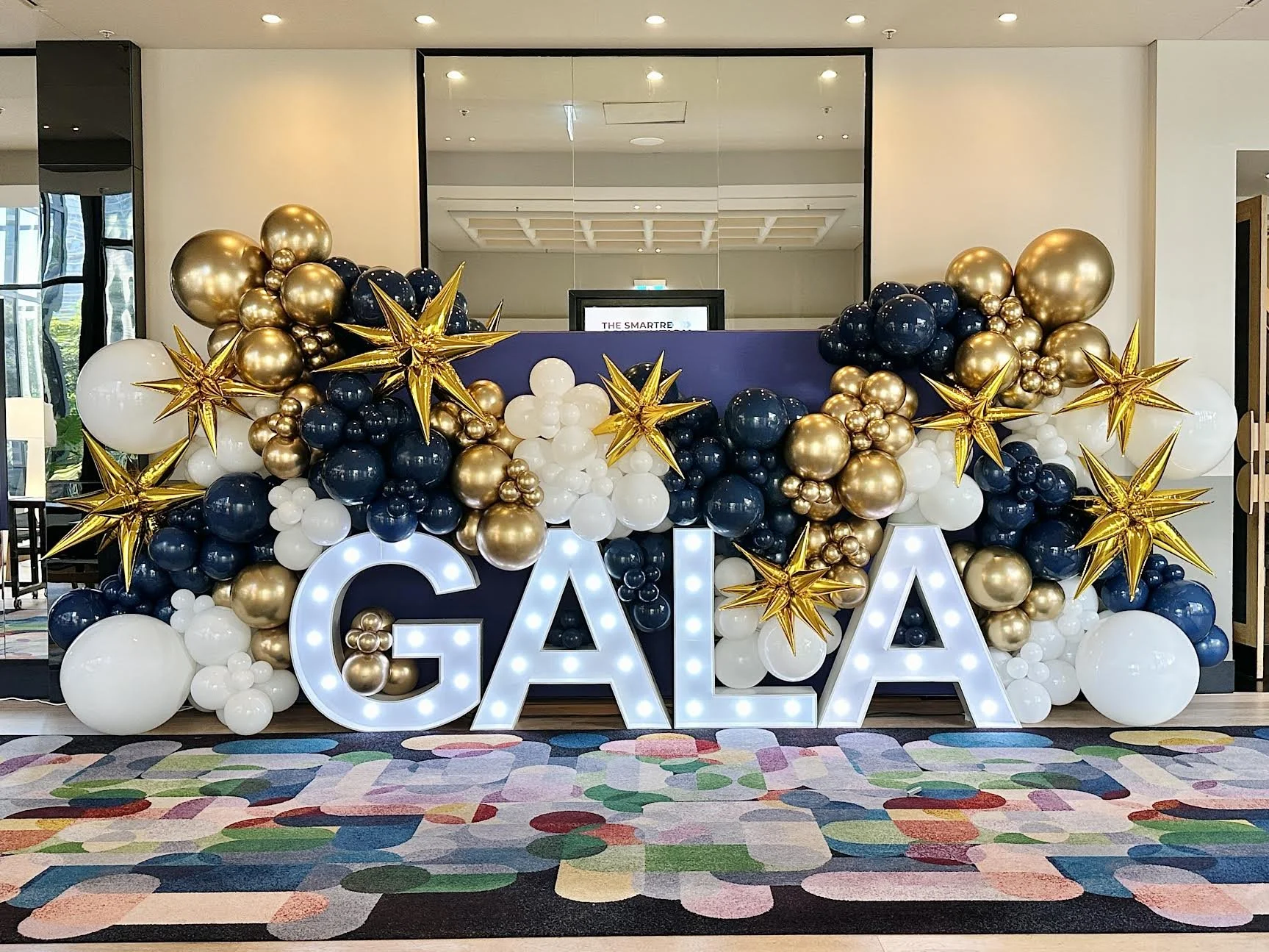 Gala event party decor featuring balloons, light up letters and a backdrop wall