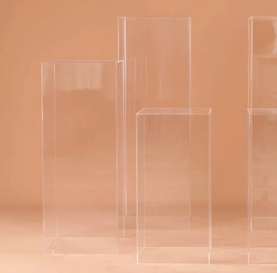 Three transparent acrylic display boxes of different heights against a peach-colored background.
