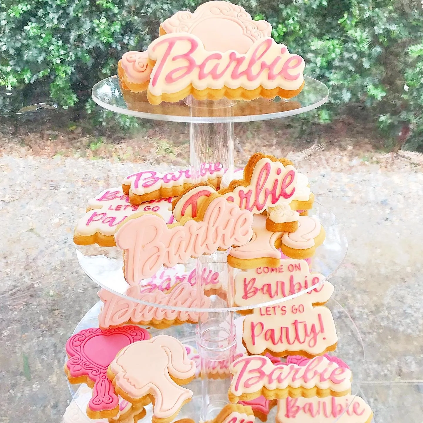 Display of Barbie decorated cookies on a clear acrylic riser for a Barbie themed birthday party