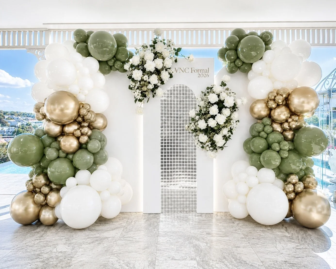 Decorative balloon arch with white, gold, and green balloons and white roses at a formal event backdrop with an arched window design and a sign that reads 'VNC Formal 2026'.