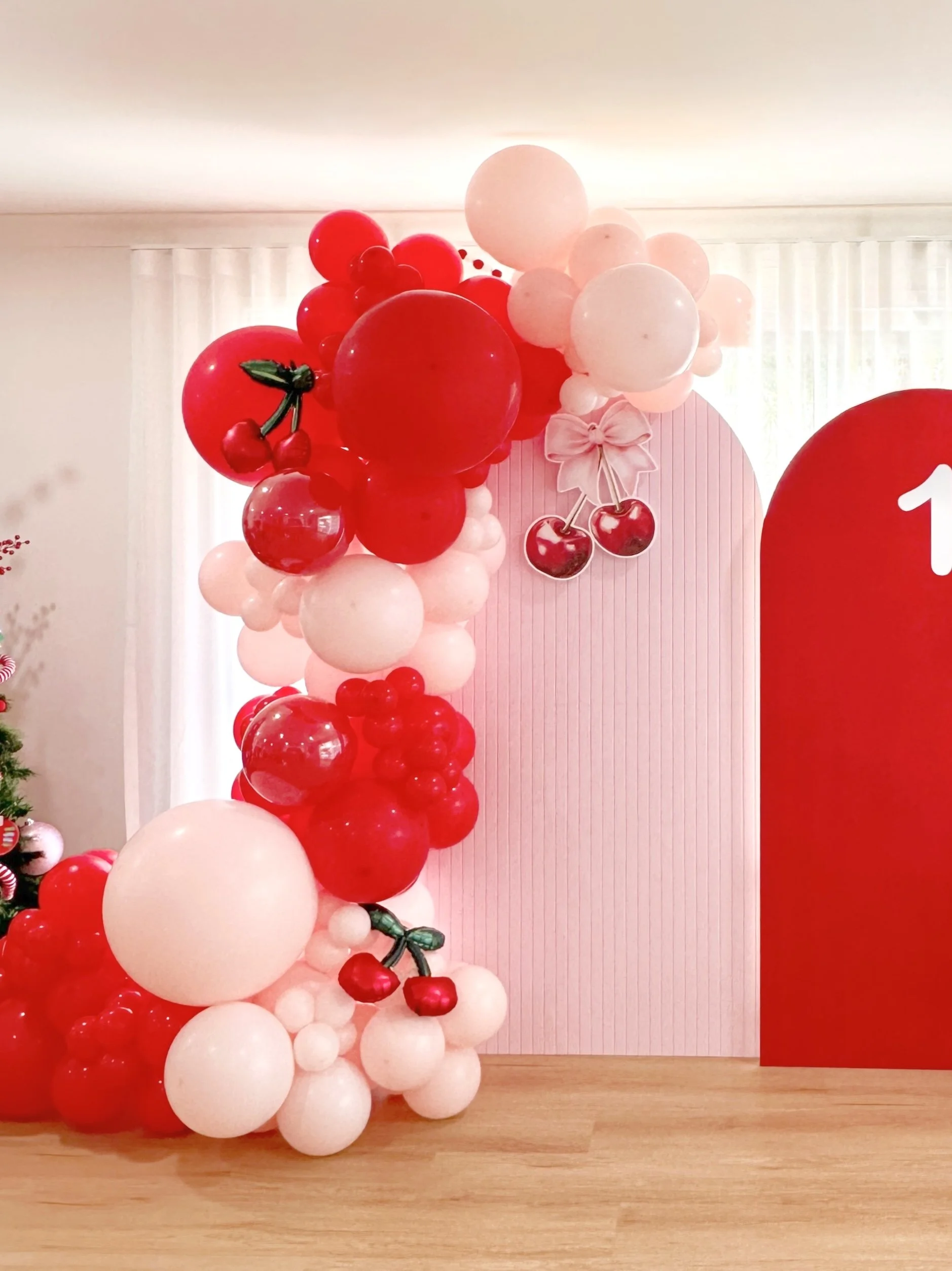 Cherry Chic 2nd birthday theme featuring balloon backdrops in pink and red and  cherries
