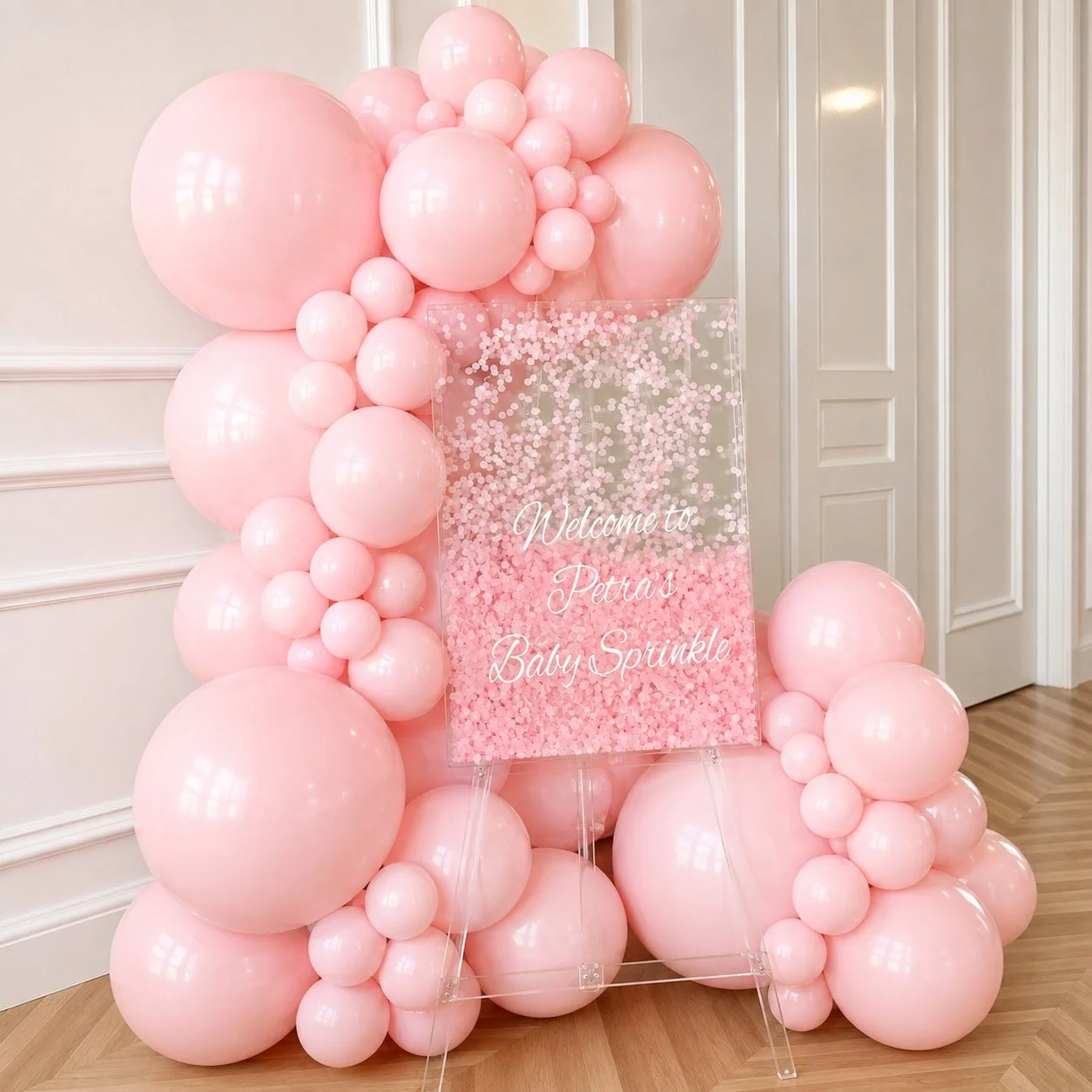 A decorative floral arrangement with pink, yellow, and purple flowers surrounded by pink and peach balloons by Print Candy