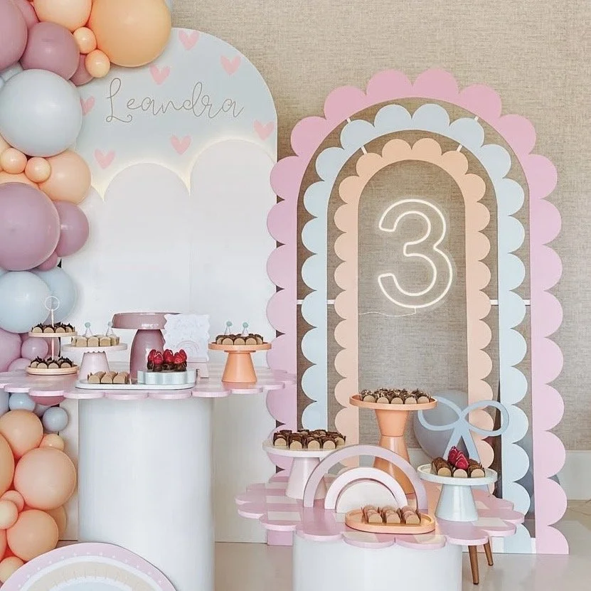 Playful and whimsical pastel birthday party setup with scalloped arch backdrop