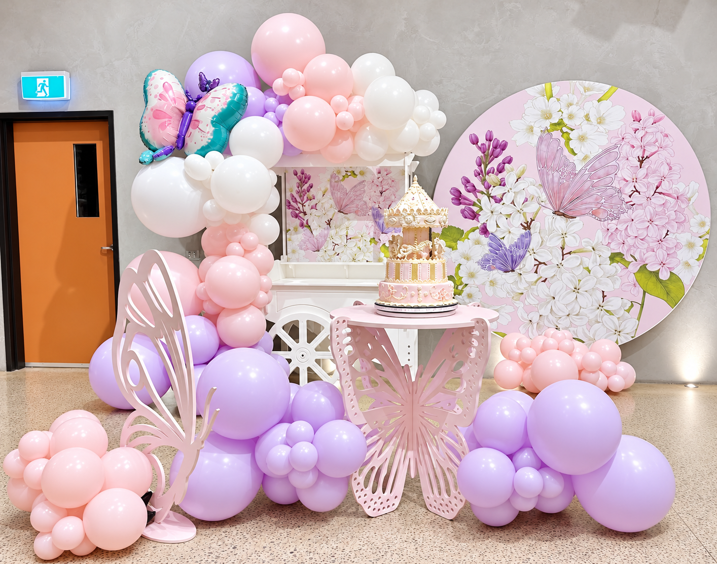 Butterfly birthday setup with butterfly round backdrop, organic balloon garland and butterfly cake table