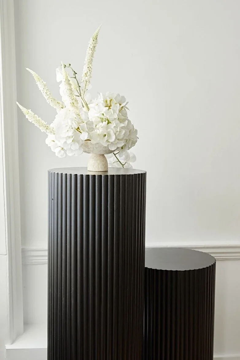 White floral arrangement hire on black rippled cake plinths