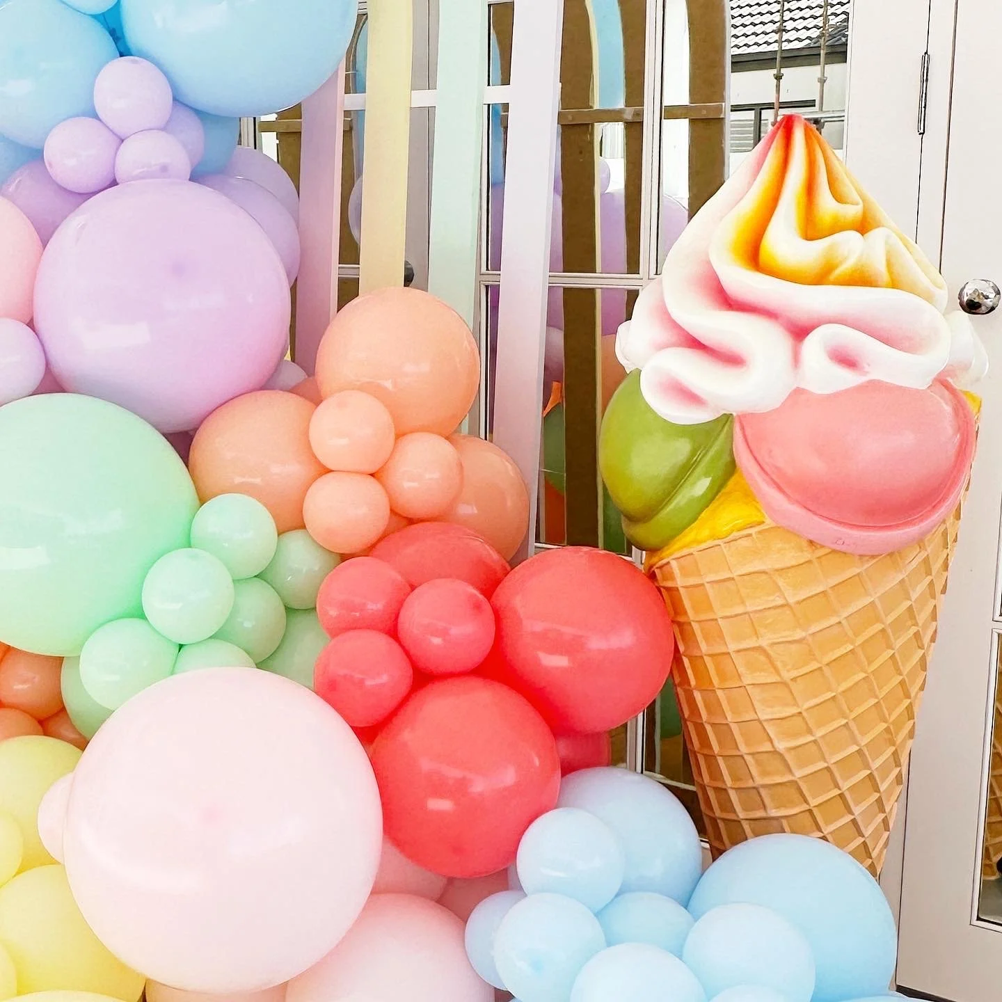 Life size ice cream prop with balloons and a rainbow arch backdrop