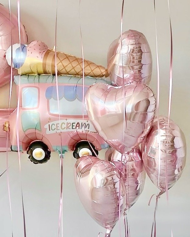 Pink balloons in the shape of hearts and a bus-themed balloon with ice cream cone and ice cream truck graphics.