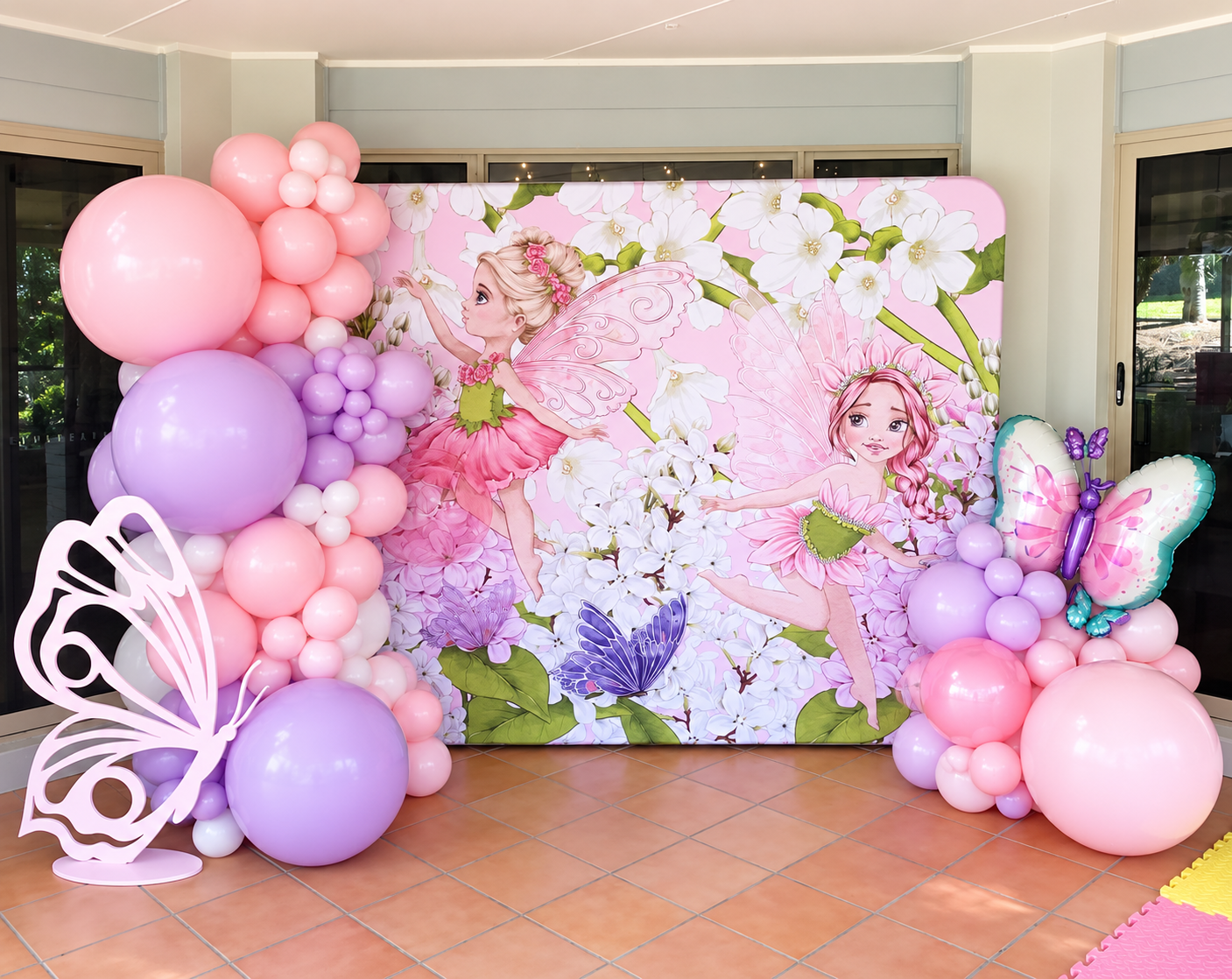 Fairy-themed party backdrop with butterfly balloons and props by Print Candy