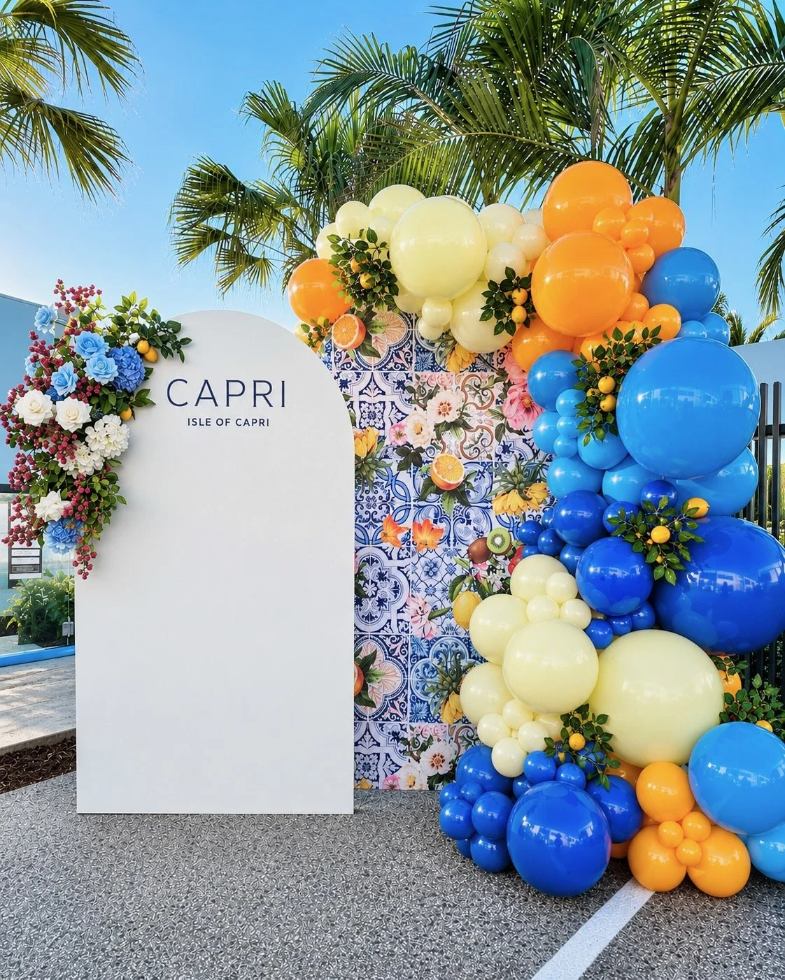 Positano Italian themed event backdrop with backdrop flowers and organic balloon garlands 
