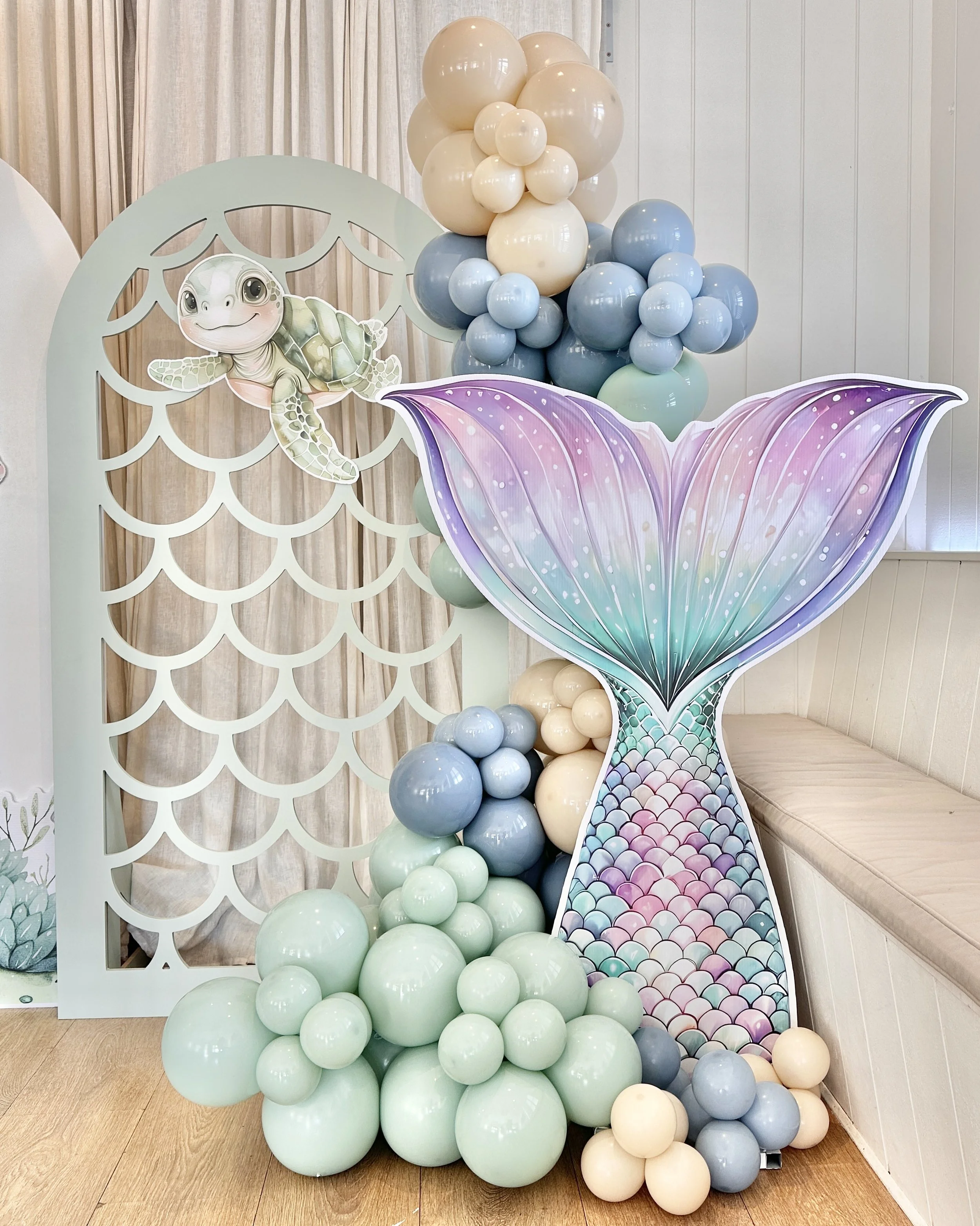 A fantastically fun mermaid party for a 2nd birthday with a mermaid scale arch backdrop, mermaid tail and baby turtle props and balloons
