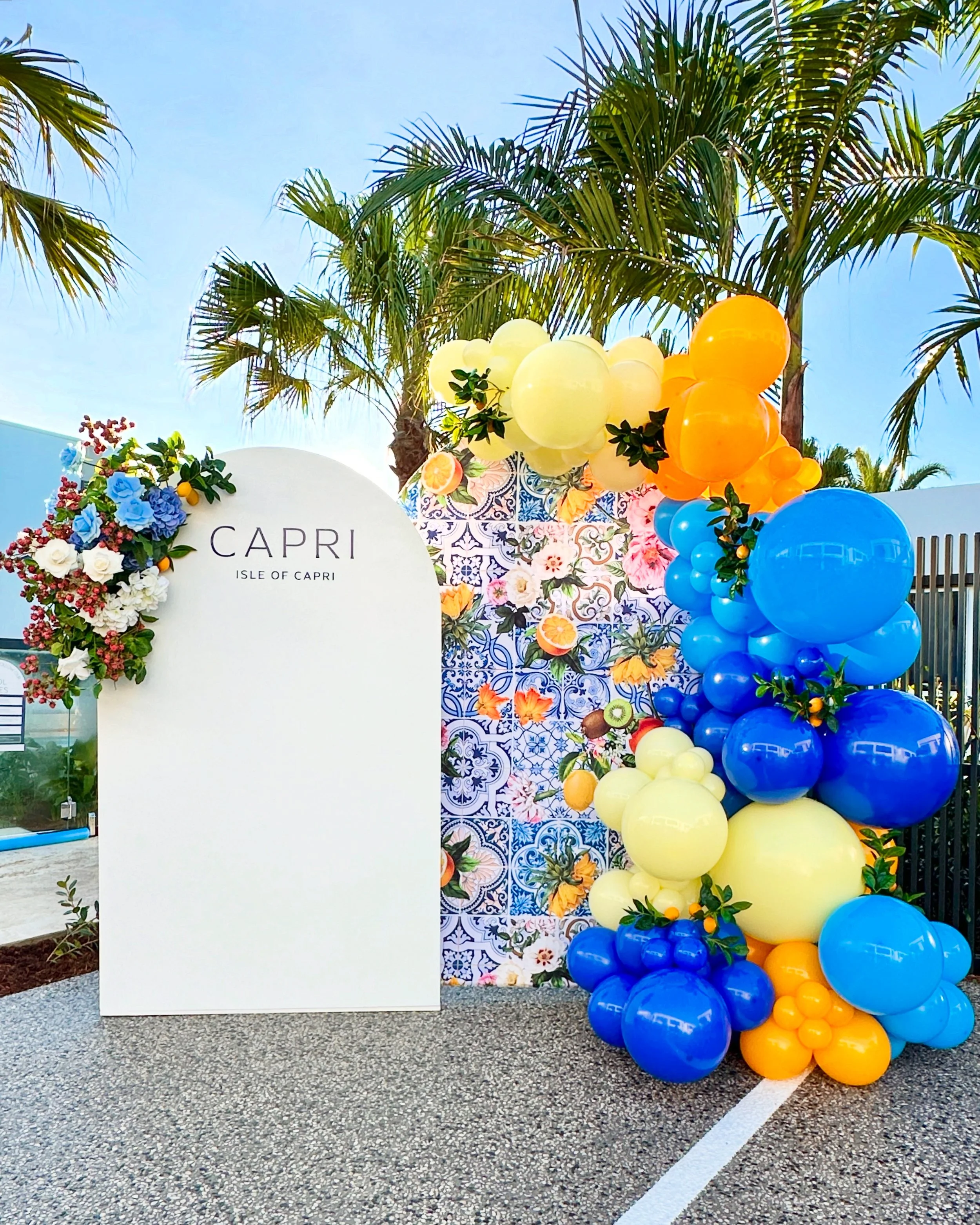 Positano themed photo backdrop with balloons and faux florals for an Amalfi Italian themed event