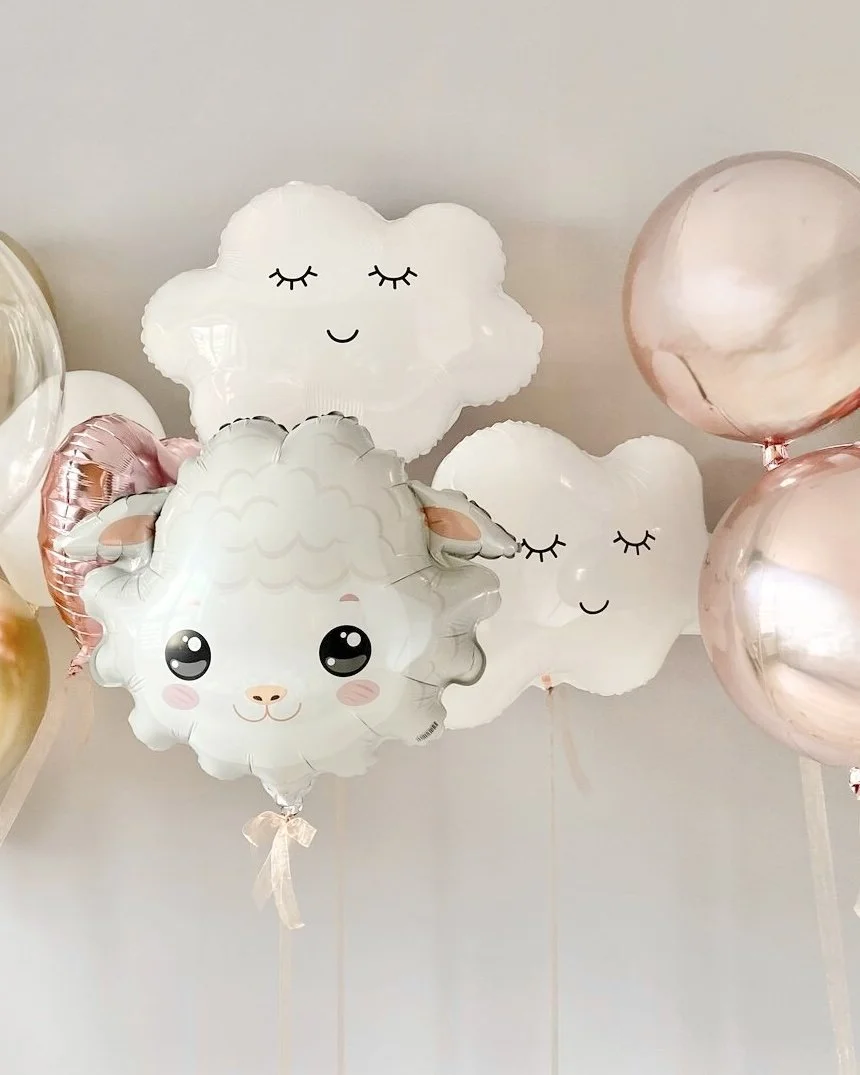 Balloon decorations including clouds and a sheep with cute, cartoon faces in soft pastel colors, likely for a baby shower or child's birthday party.