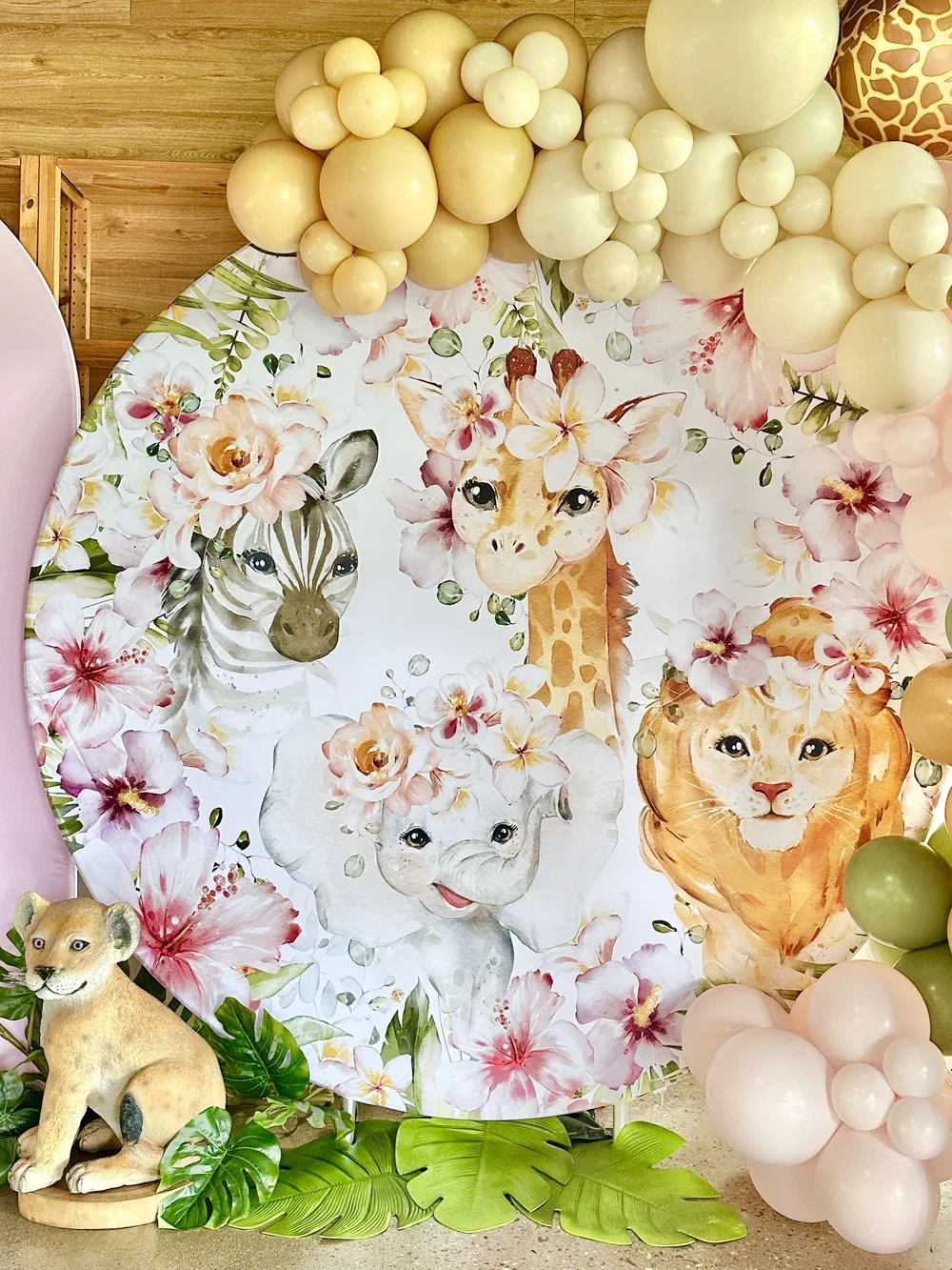 Round floral safari themed backdrop including a zebra, giraffe, elephant, and lion surrounded by pink and white flowers
